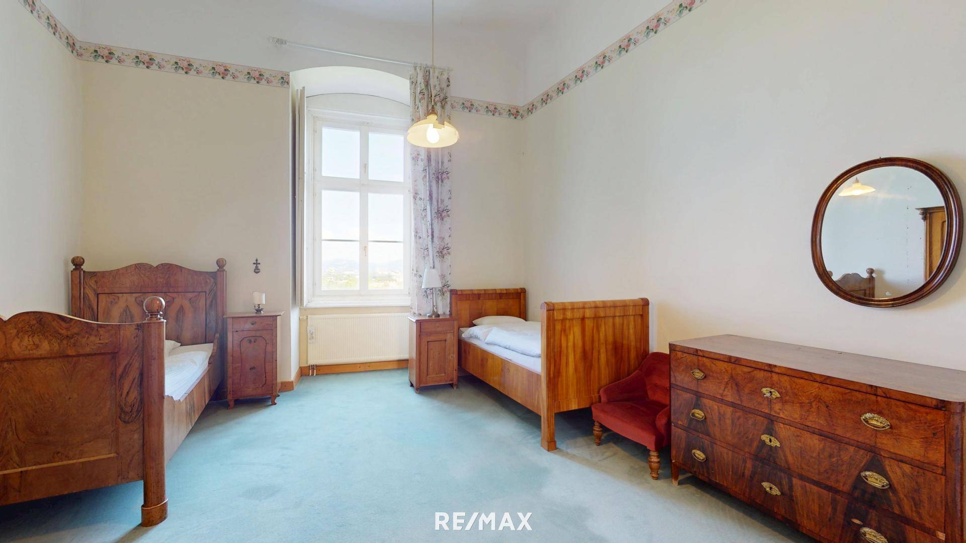 Gemütliches Schlafzimmer mit zwei Holzbetten, antiker Kommode und großem Fenster.