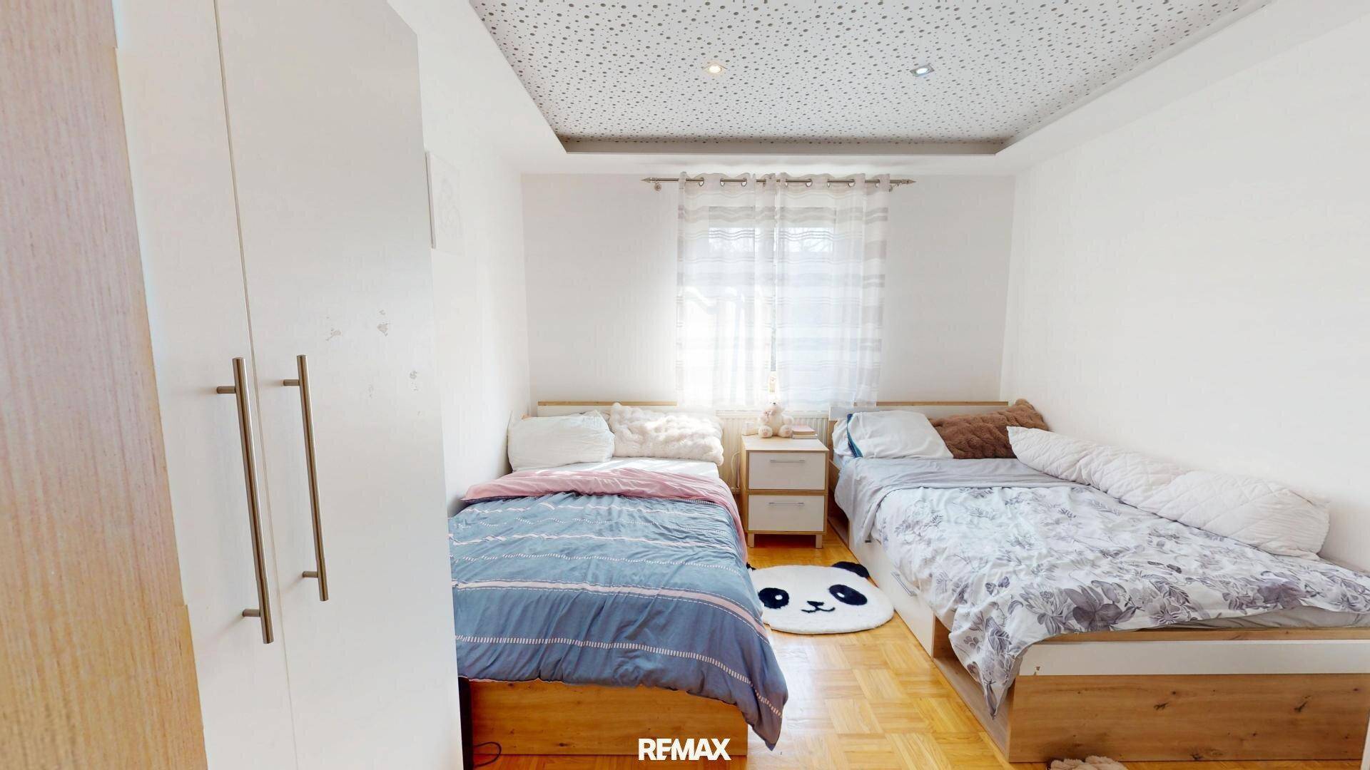 Helles Schlafzimmer mit zwei Betten und einem großen Kleiderschrank.