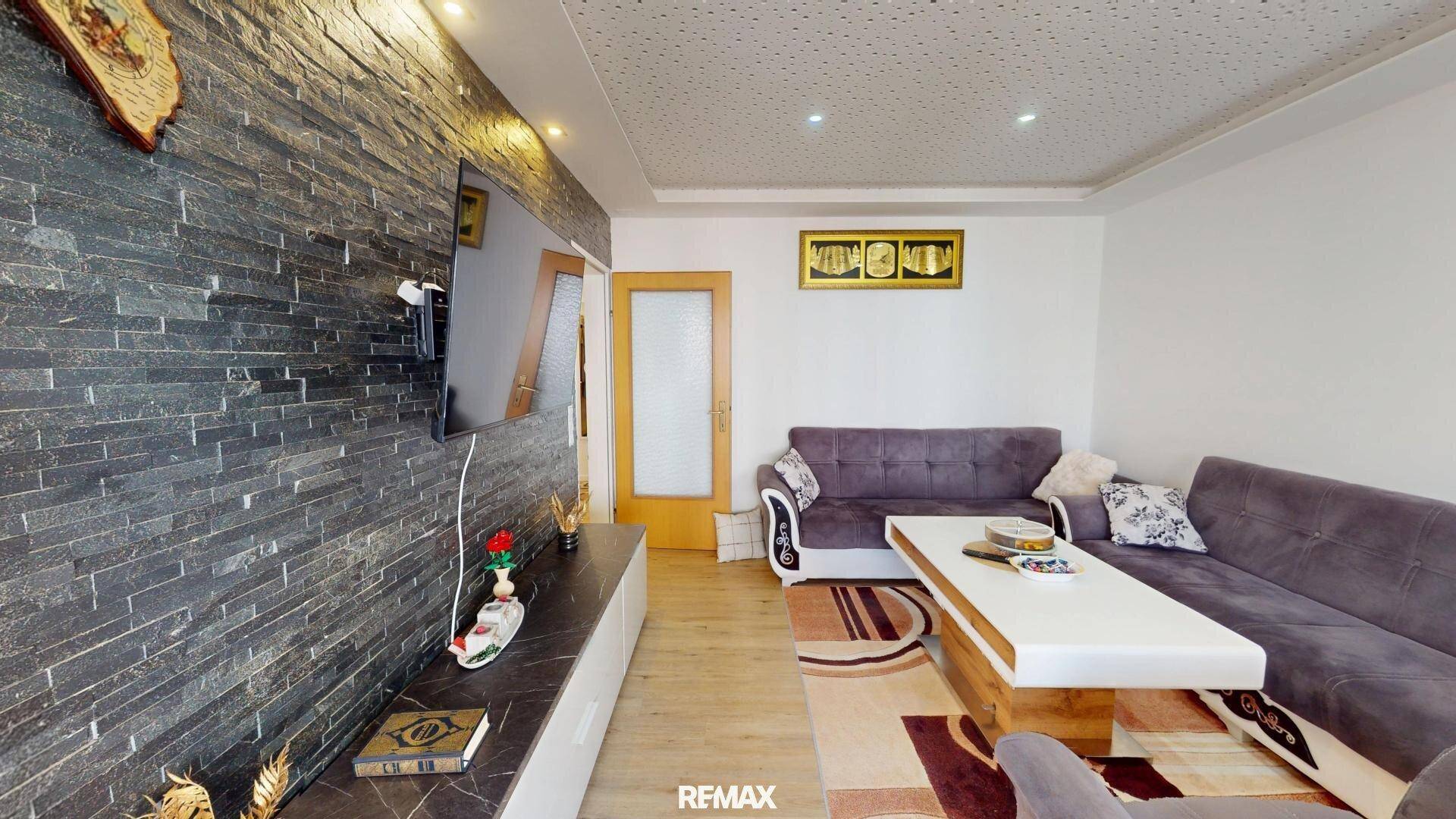 Modernes Wohnzimmer mit großem Sofa, Couchtisch und dekorativer Steinwand.
