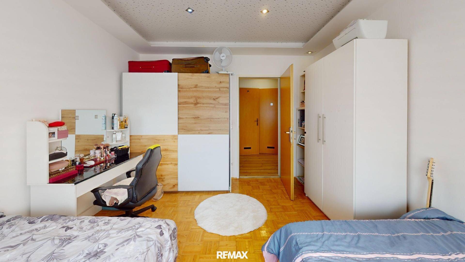 Geräumiges Schlafzimmer mit zwei Betten, Schreibtisch und Kleiderschränken.
