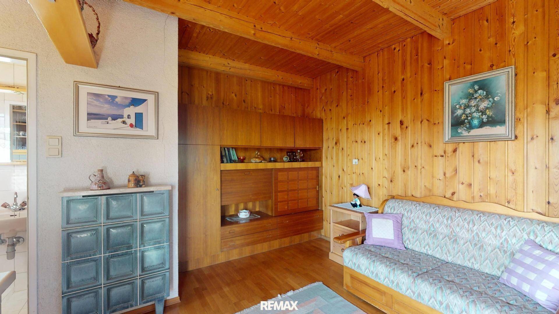 Wohnzimmer mit Holzvertäfelung, traditionellem Kachelofen und gemütlichem Sofa.