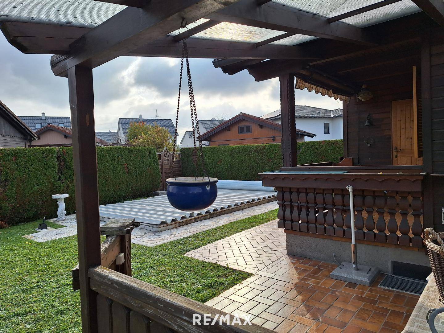 Blick vom überdachten Terrassenbereich auf den Garten mit abgedecktem Pool.