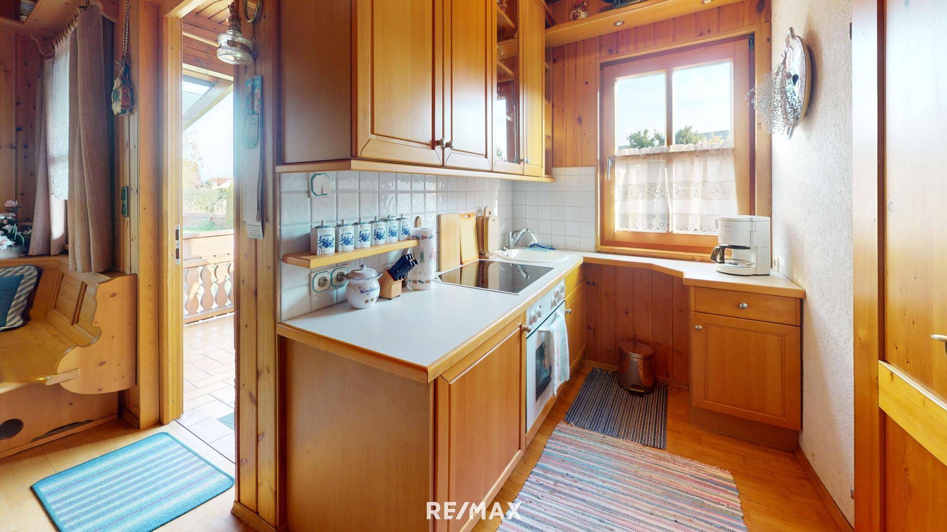 Kleine, funktionale Küche mit Holzschränken, Herd und Fenster, im traditionellen Stil gehalten.