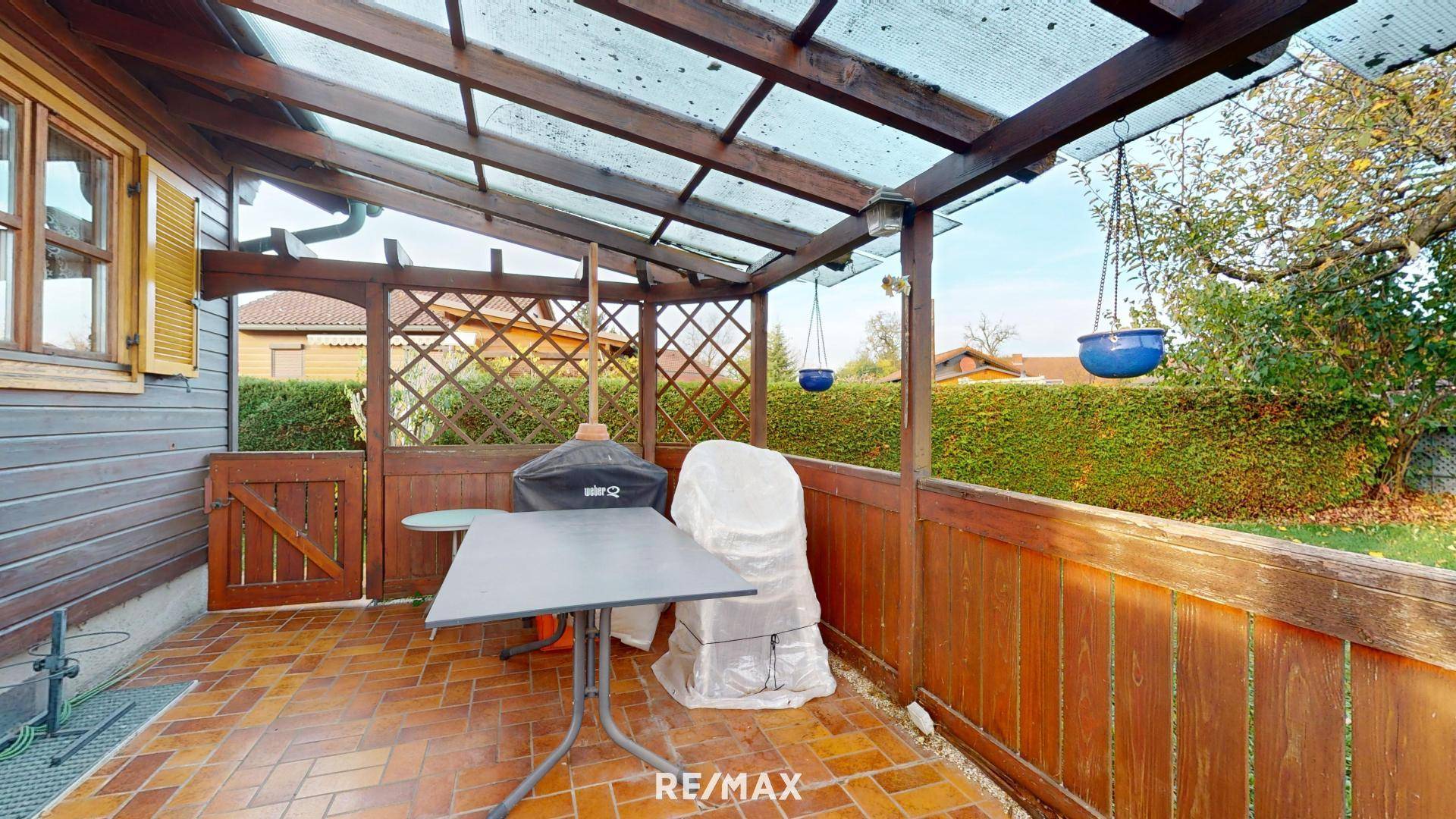 Überdachte Terrasse mit Grillbereich und Blick auf den gepflegten Garten.