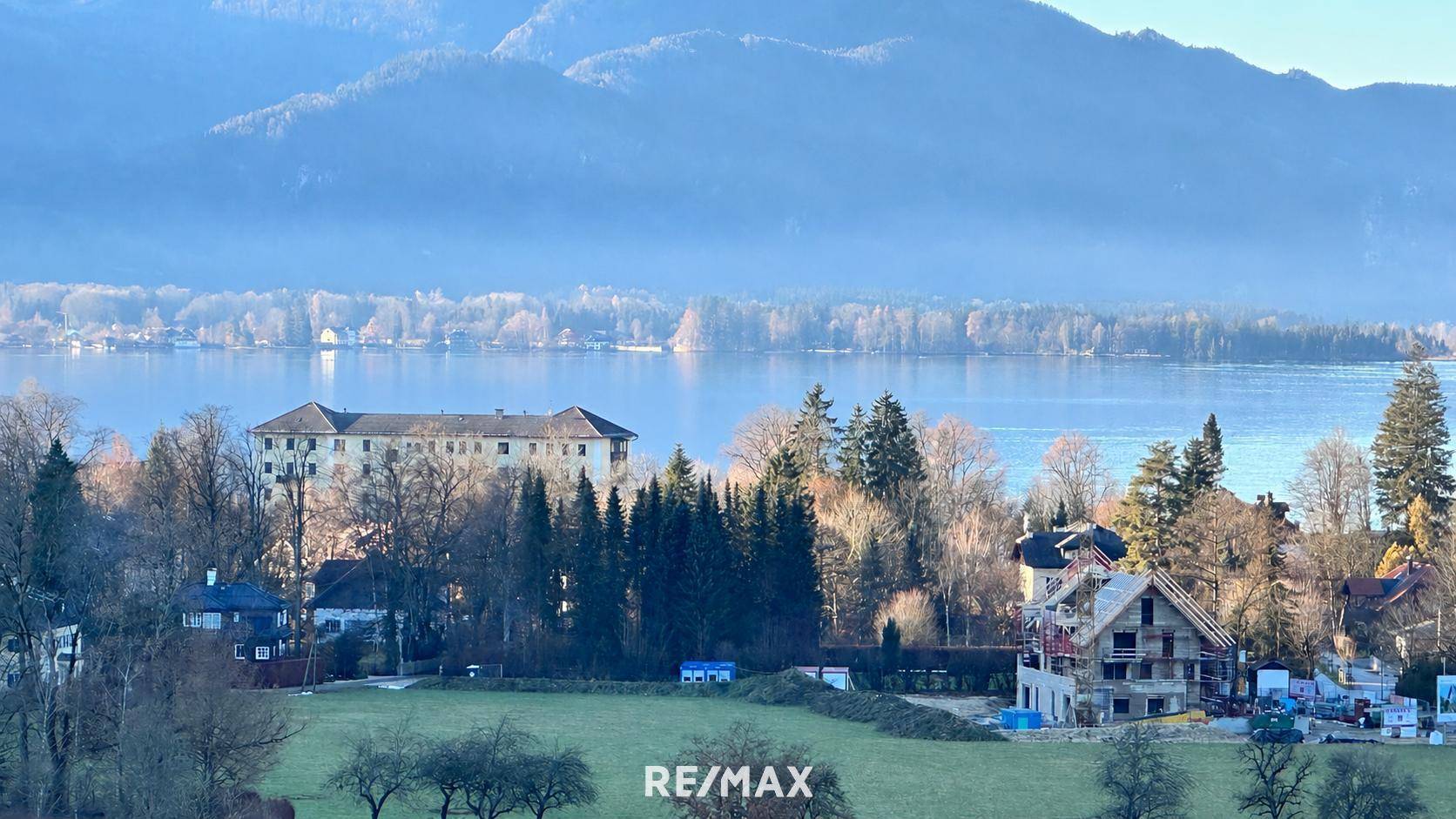 Weitläufiger Blick über den Wolfgangsee mit bewaldeten Ufern und traditionellen Gebäuden.