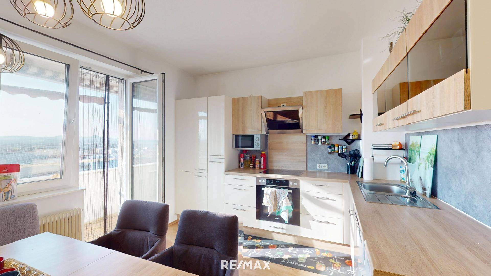 Moderne Küche mit hellen Holz- und weißen Schränken, integrierten Geräten und Balkonzugang.