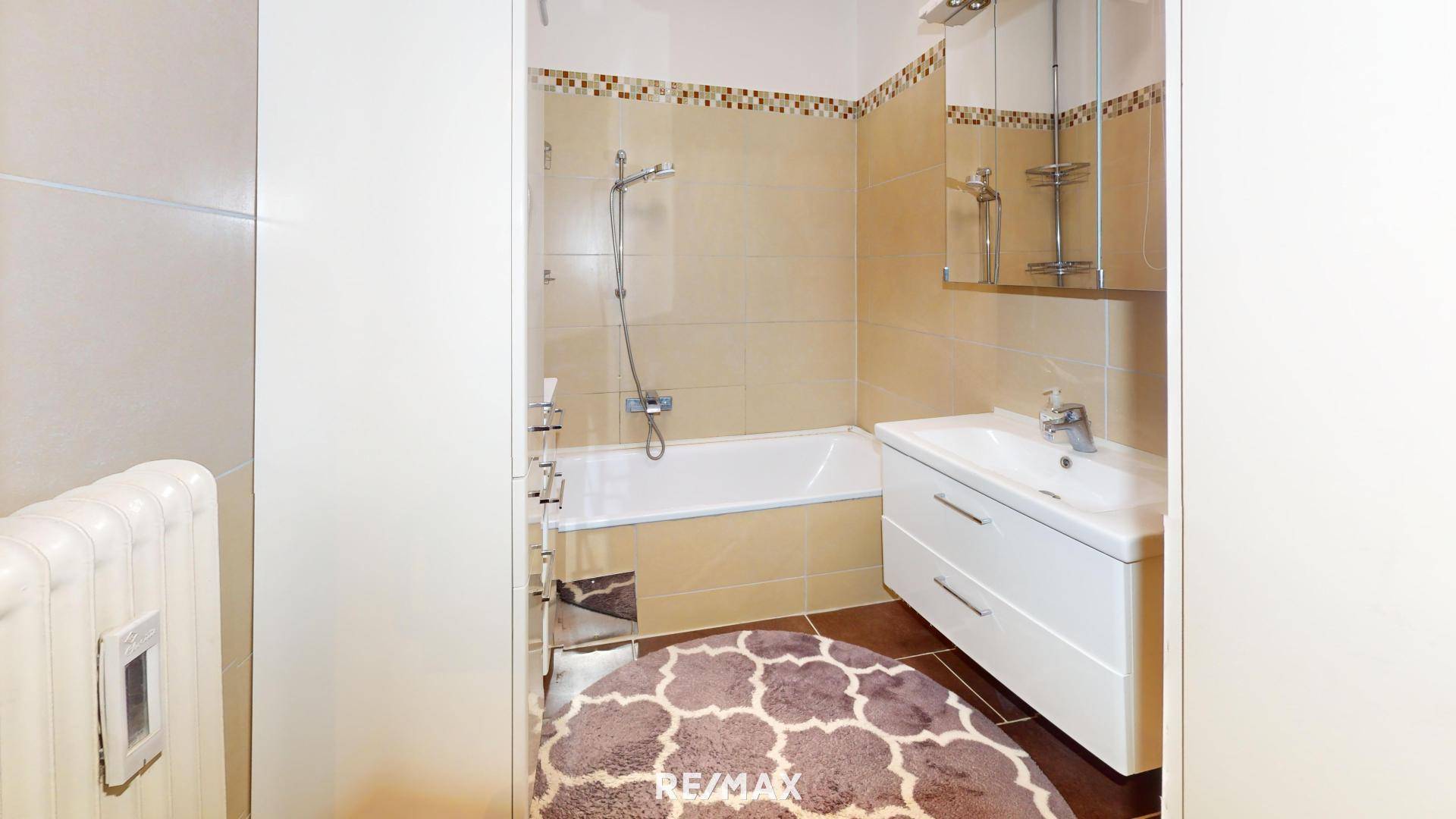 Funktionales Badezimmer mit Badewanne, Waschbecken und hellen Fliesen.