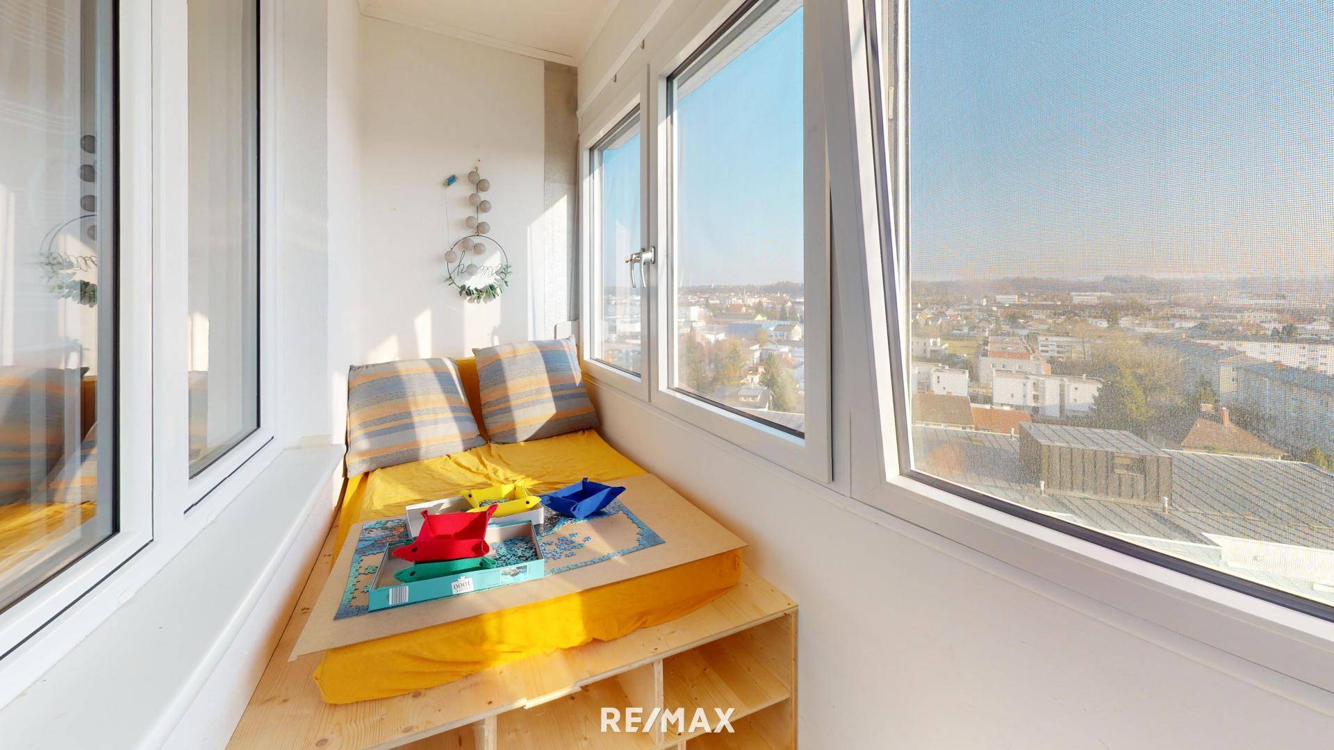Helle Loggia mit gemütlicher Sitzbank und weitem Blick über die Stadt.