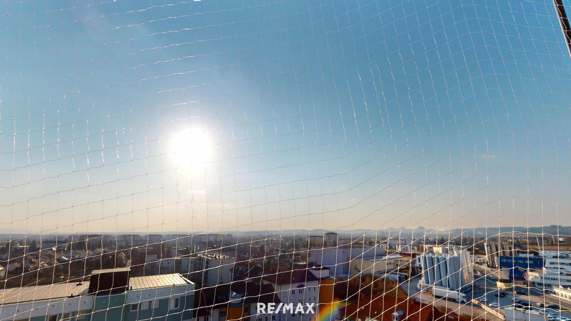 Sonniger Ausblick über die Stadt durch ein Schutznetz.