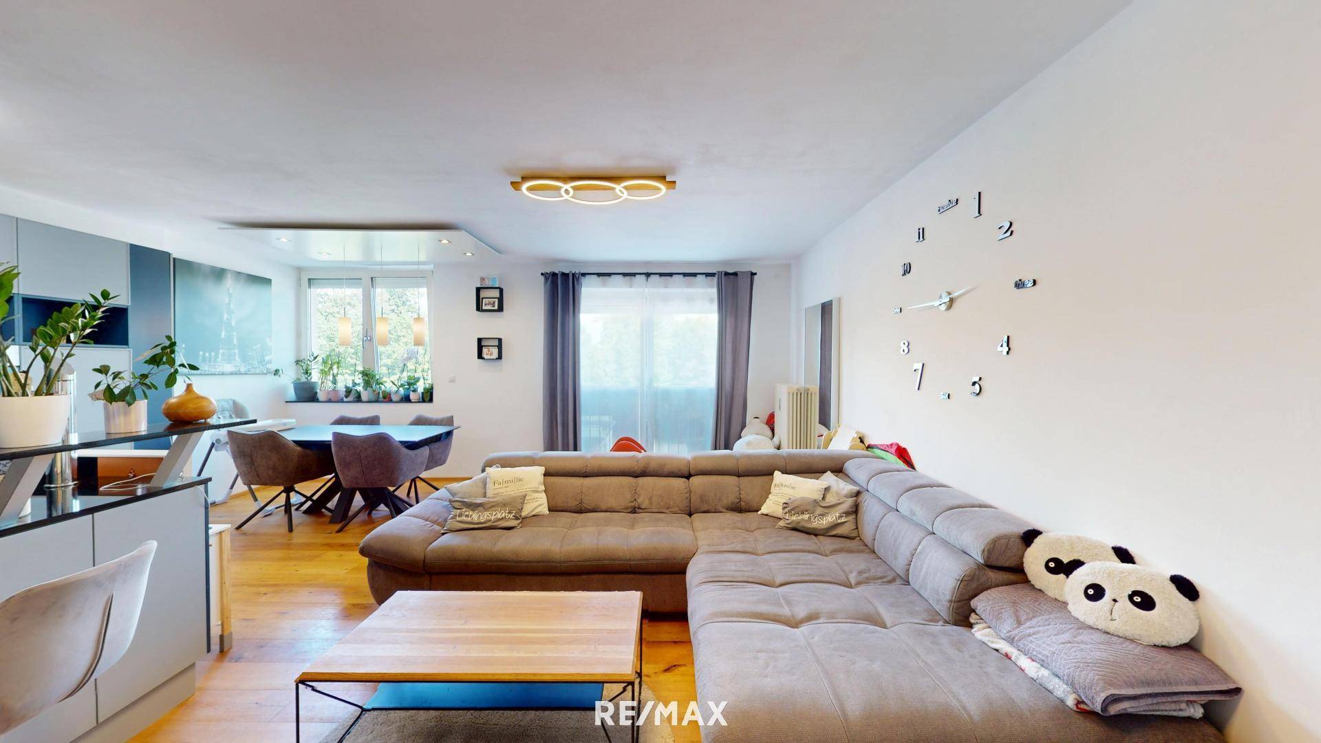 Gemütlicher Wohnbereich mit großem Ecksofa und angrenzendem Essbereich mit Holzboden.