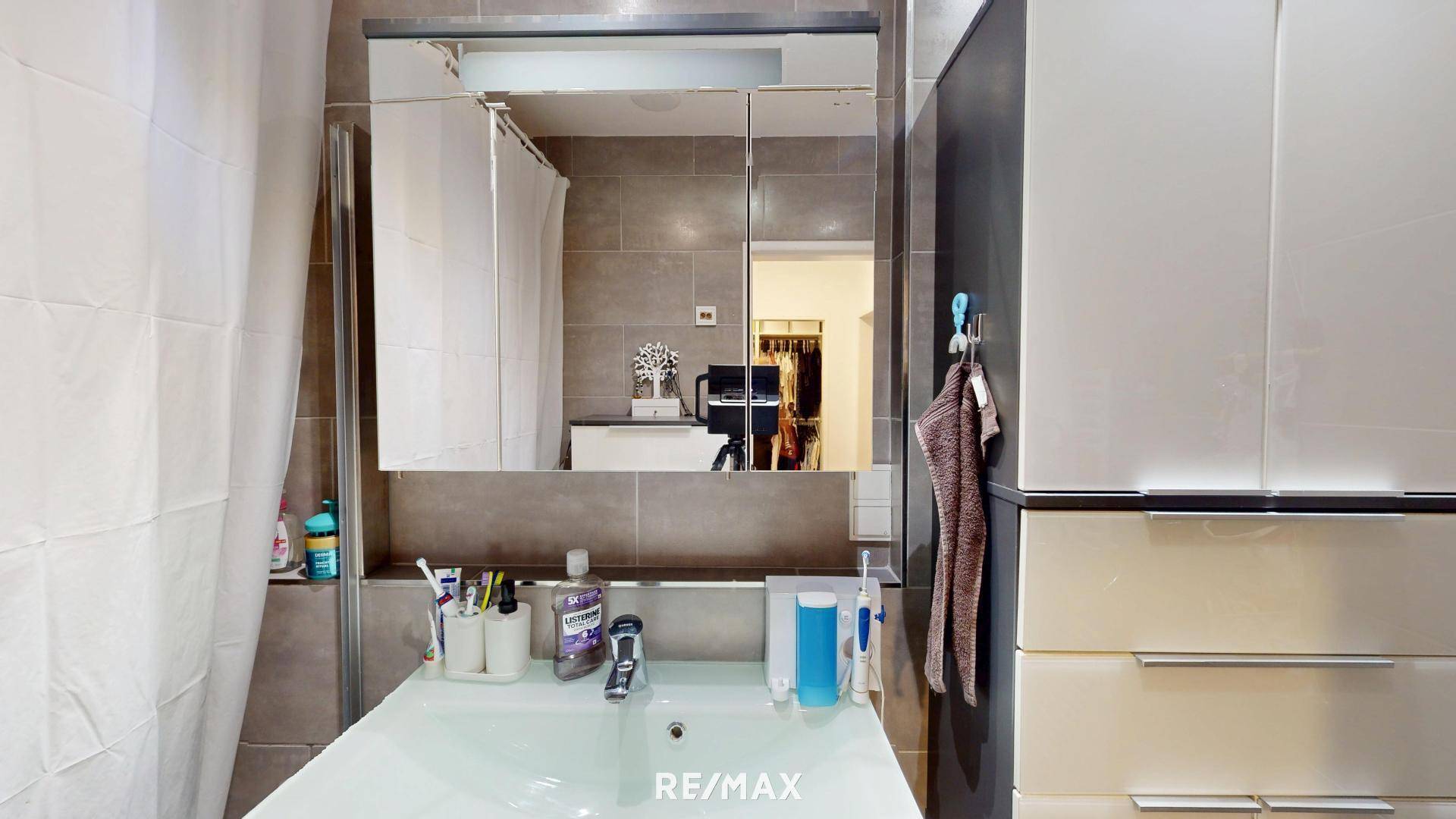 Badezimmer mit modernem Waschbecken, Spiegelschrank und Duschbereich mit Fliesen.