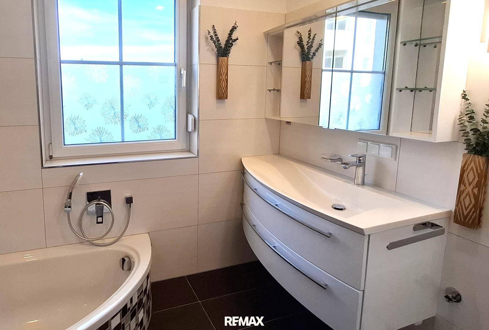 Modernes Badezimmer mit Eckbadewanne, stilvollem Waschtisch und Spiegelschrank.