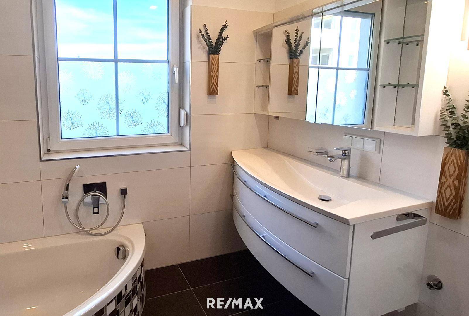 Modernes Badezimmer mit Eckbadewanne, stilvollem Waschtisch und Spiegelschrank.