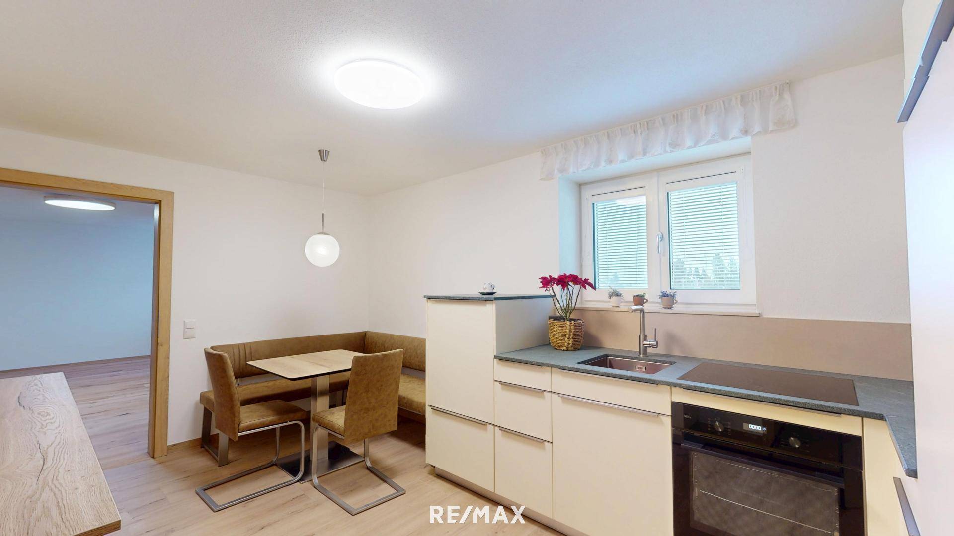 Moderne Küche mit heller Einbauküche, Essbereich und Fenster, perfekt für gemeinsame Mahlzeiten.