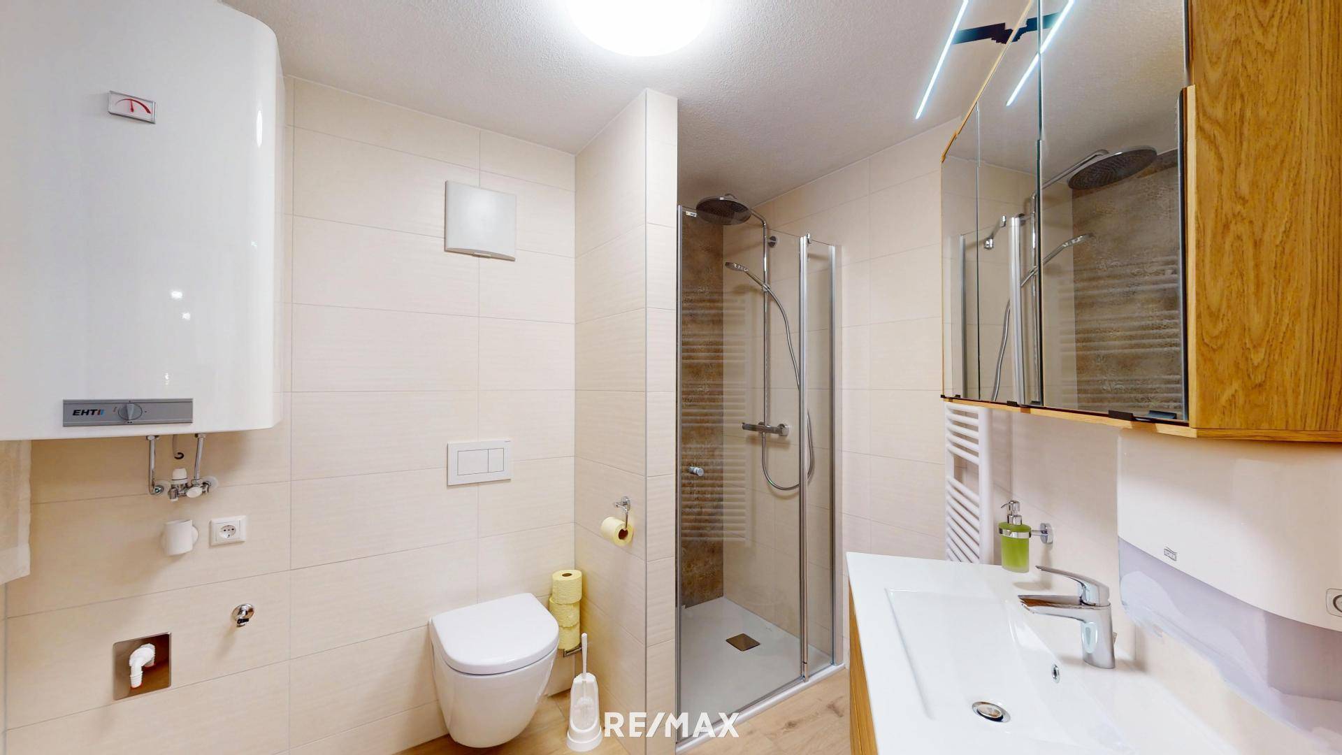 Modernes Badezimmer mit begehbarer Dusche, WC, Waschbecken und hellen Fliesen, sehr gepflegt.