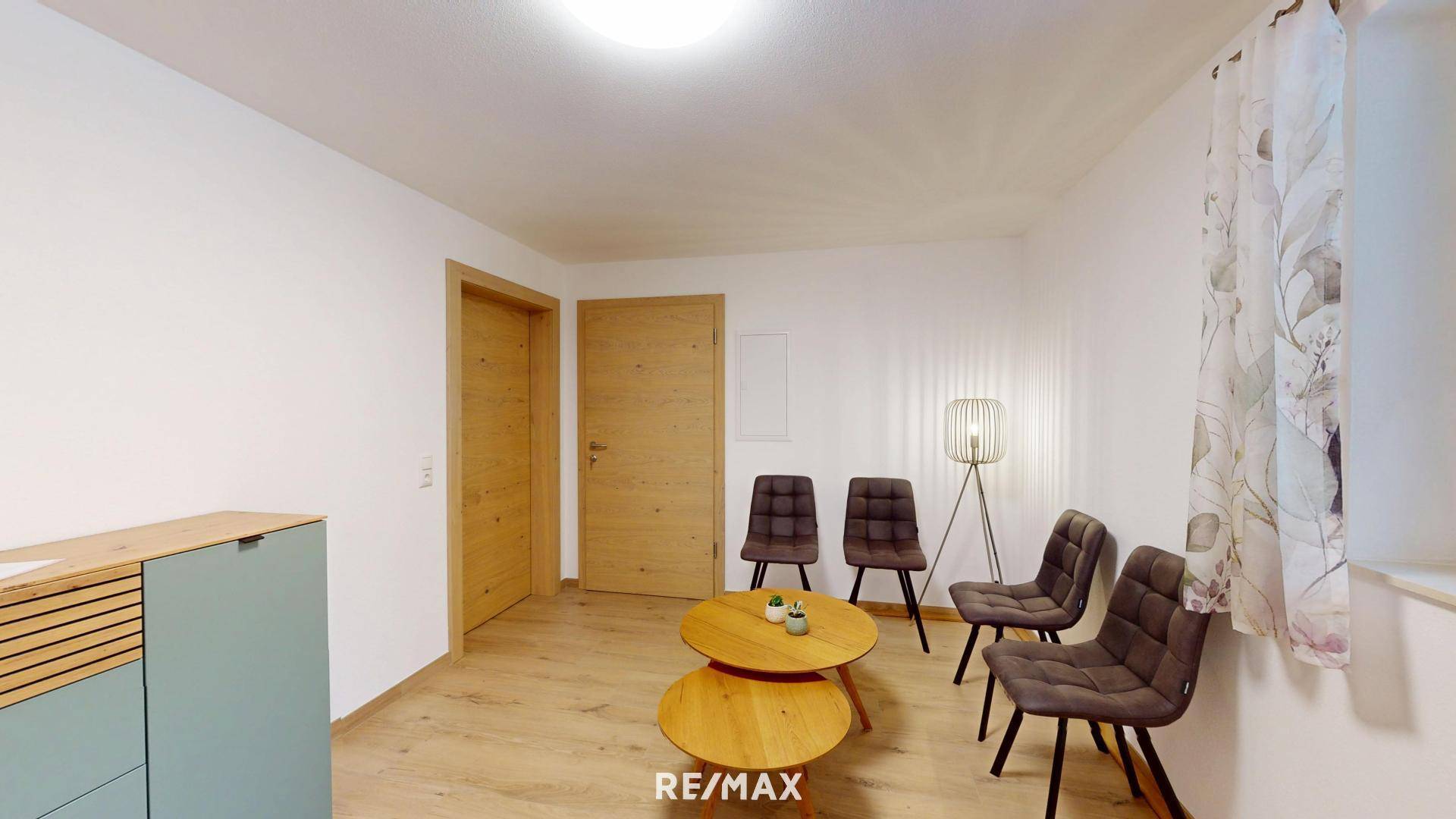 Gemütlicher Wohnbereich mit Holzboden, kleinem Couchtisch und bequemen Stühlen, ideal für Gäste.