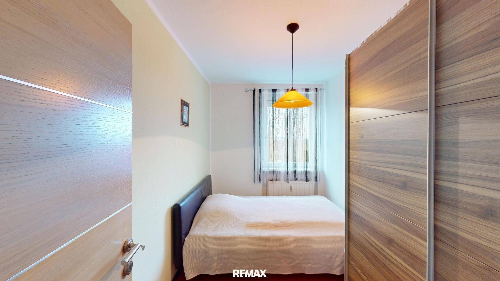 Gemütliches Schlafzimmer mit Doppelbett, Holzschrank und Fenster.