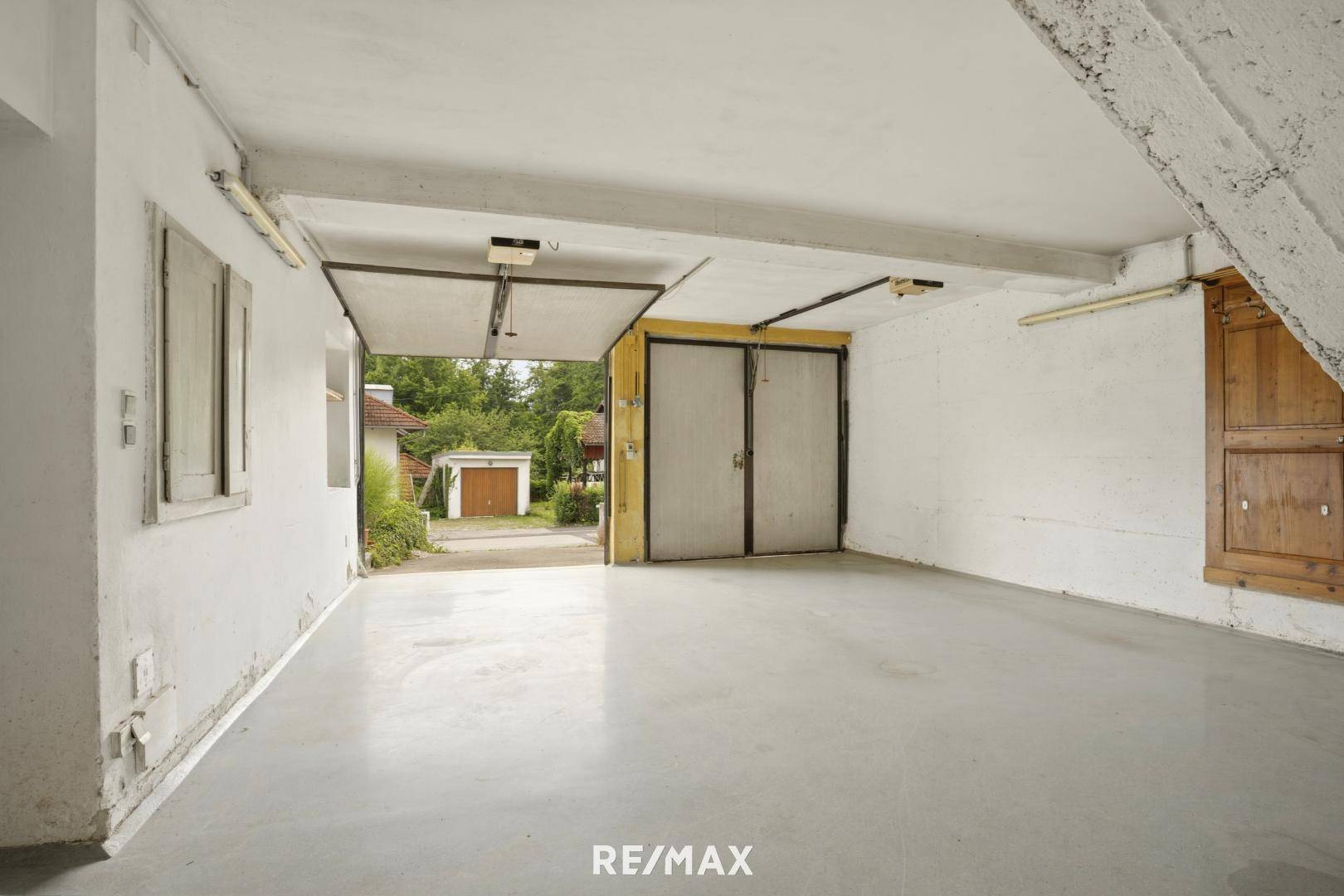 Geräumige Garage mit Betonboden und Zugang zum Außenbereich des Hauses.