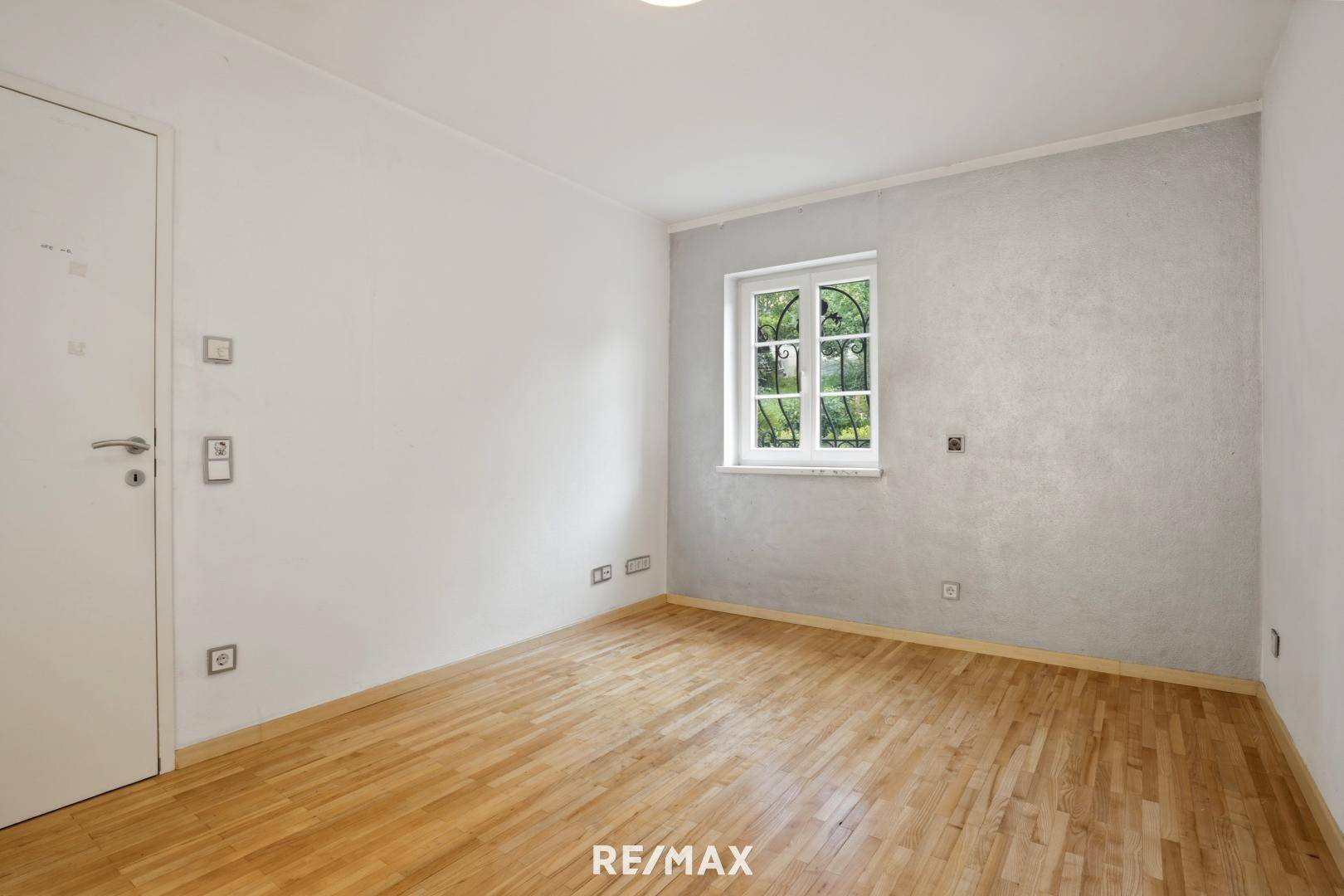 Helles Zimmer mit Holzboden und einem Fenster, ideal als Schlaf- oder Arbeitszimmer.