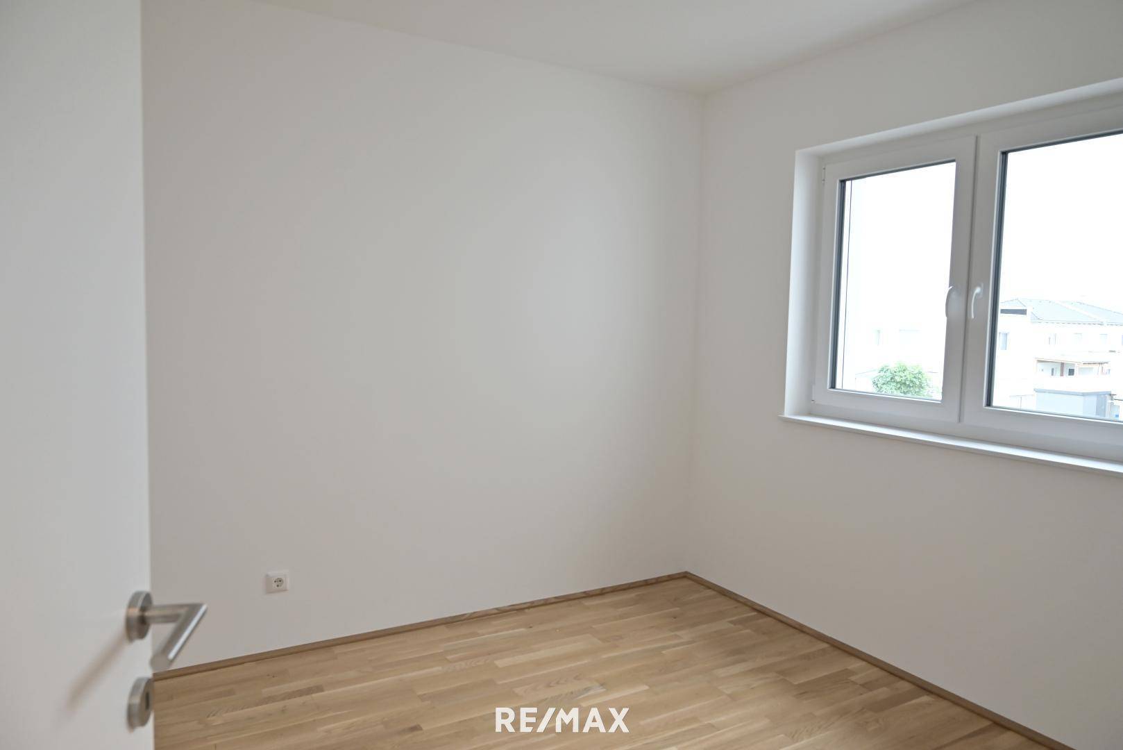 Helles Schlafzimmer mit Holzboden und großem Fenster für viel Tageslicht.
