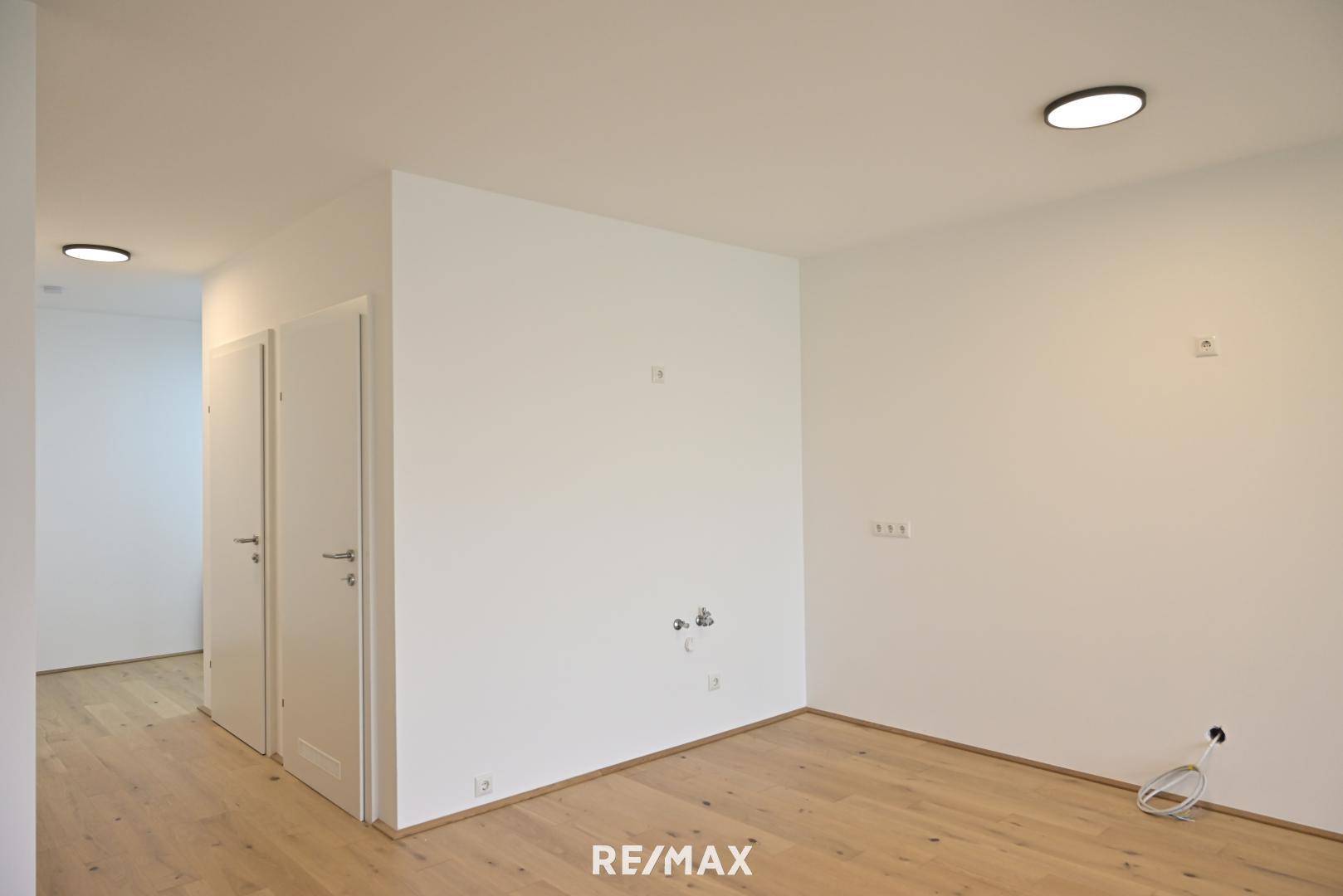 Leerer Raum mit Holzboden und zwei Türen, bereit für die individuelle Gestaltung.