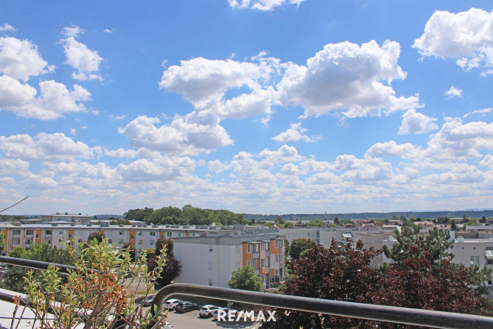 Weiter Blick von einem Balkon über eine Wohnsiedlung unter einem strahlend blauen Himmel.