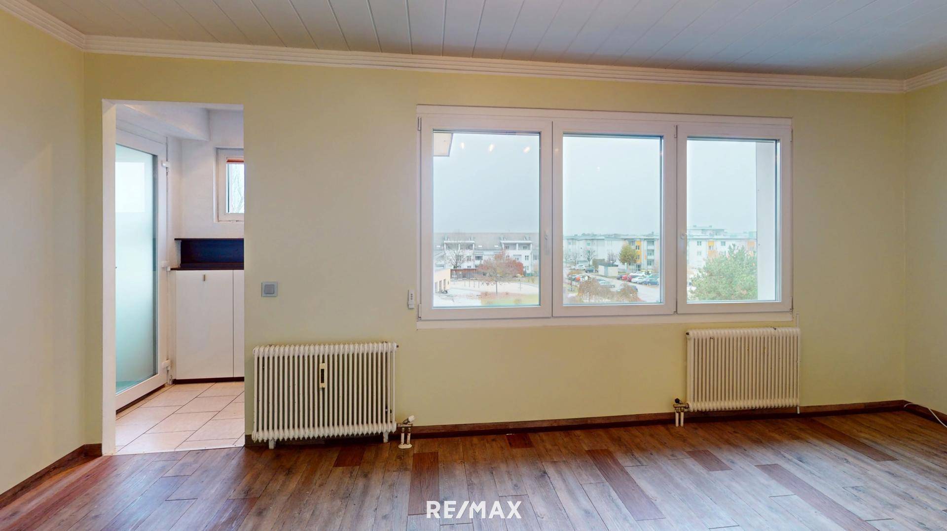 Helles Wohnzimmer mit Holzfußboden, großen Fenstern und einem angenehmen Blick ins Grüne.