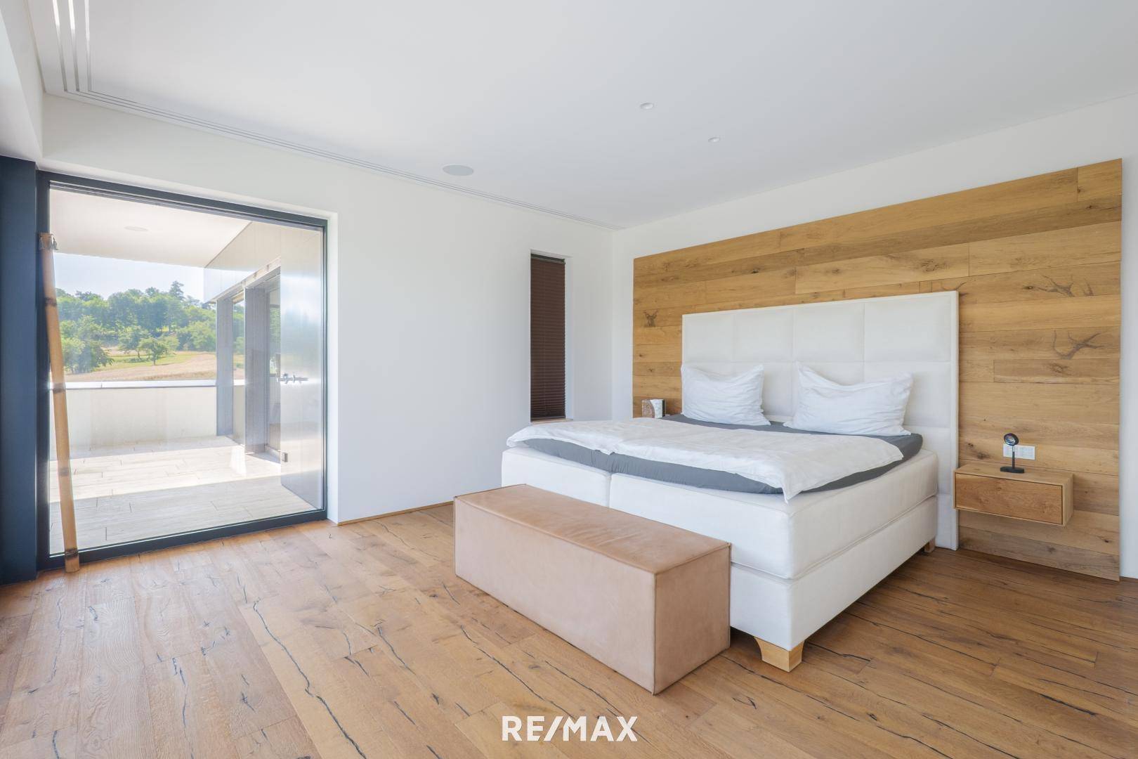Helles Schlafzimmer mit großem Bett, Holzboden und direktem Zugang zu einem Balkon mit Aussicht.