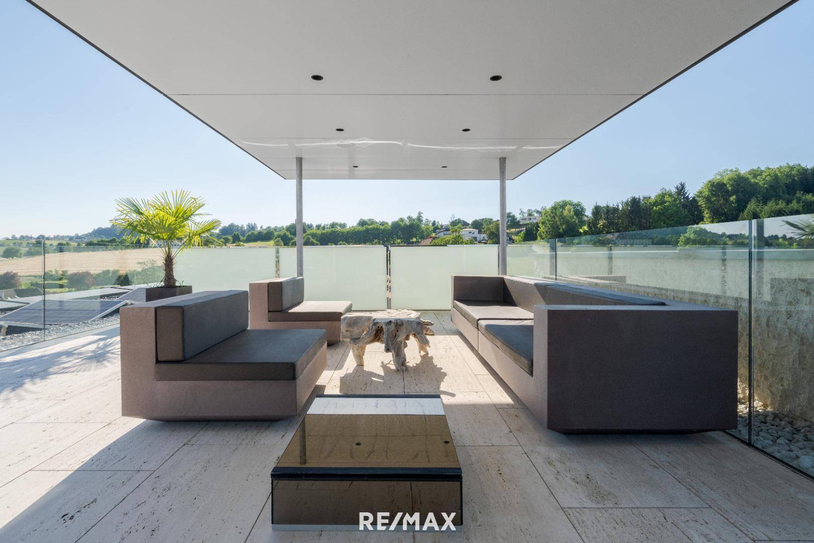 Überdachte Terrasse mit modernen Lounge-Möbeln und weitem Blick über die grüne Landschaft.