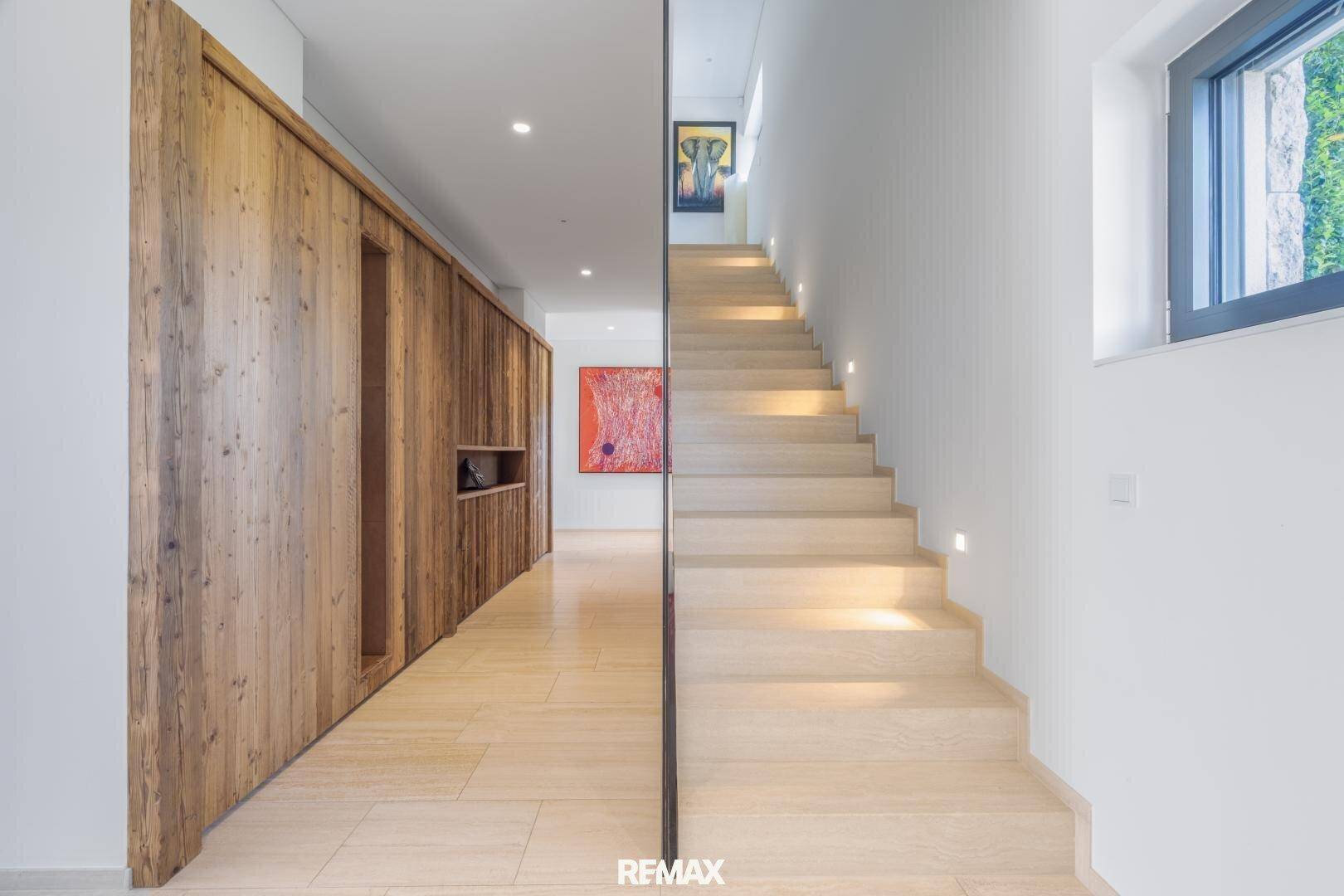 Heller Flur mit Holzvertäfelung, moderner Treppe und minimalistischer Beleuchtung.