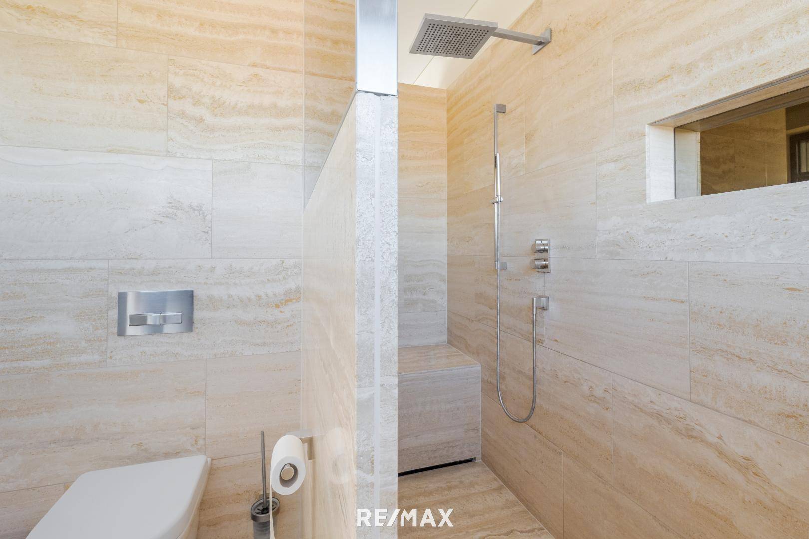 Modernes Badezimmer mit ebenerdiger Dusche, Wand-WC und beigefarbenen Natursteinfliesen.