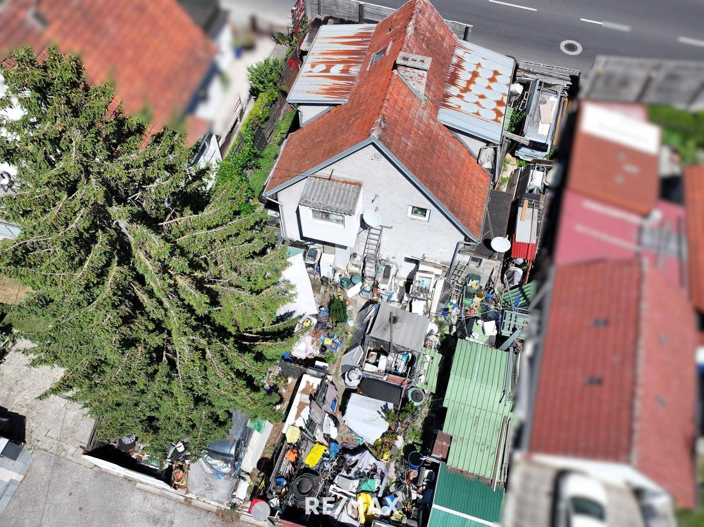 Überblick aus der Luft auf ein Wohnhaus mit rotem Dach und einem sehr unordentlichen Gartenbereich.