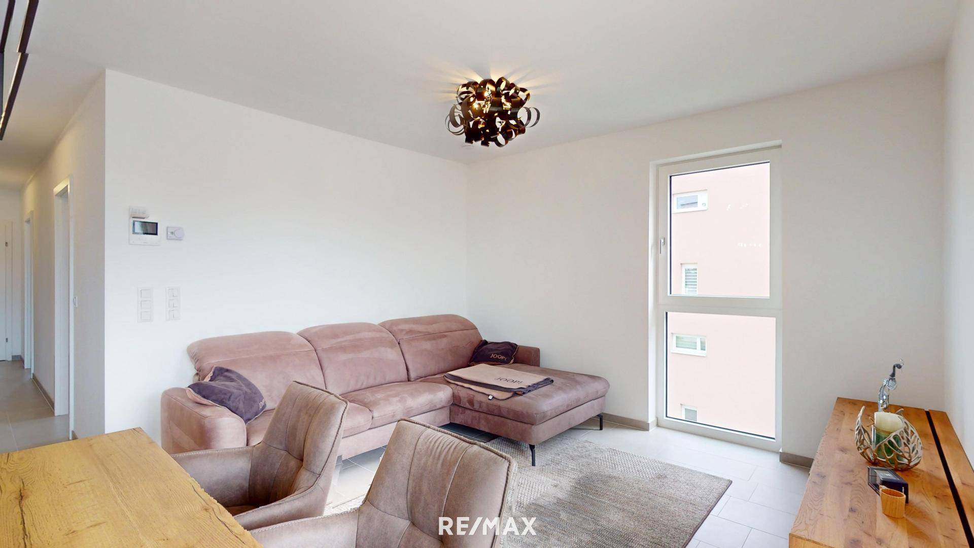 Gemütliches Wohnzimmer mit einem großen Ecksofa und hellem Fenster.