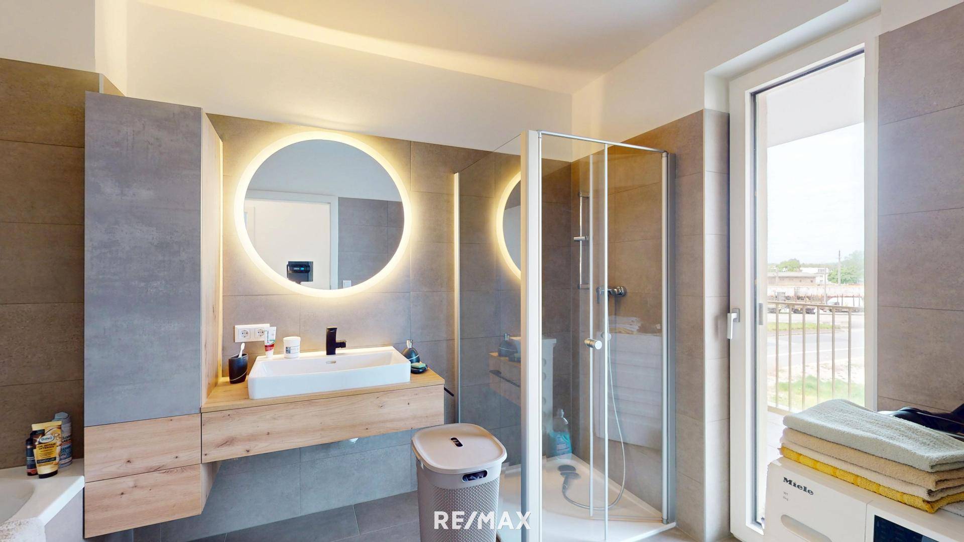 Modernes Badezimmer mit runden Spiegeln, begehbarer Dusche und Fenster.