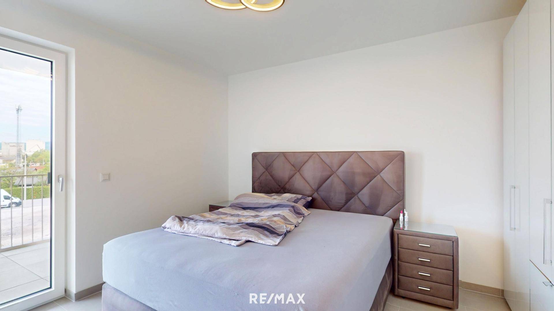 Modernes Schlafzimmer mit großem Bett, Nachttischen und Zugang zum Balkon.