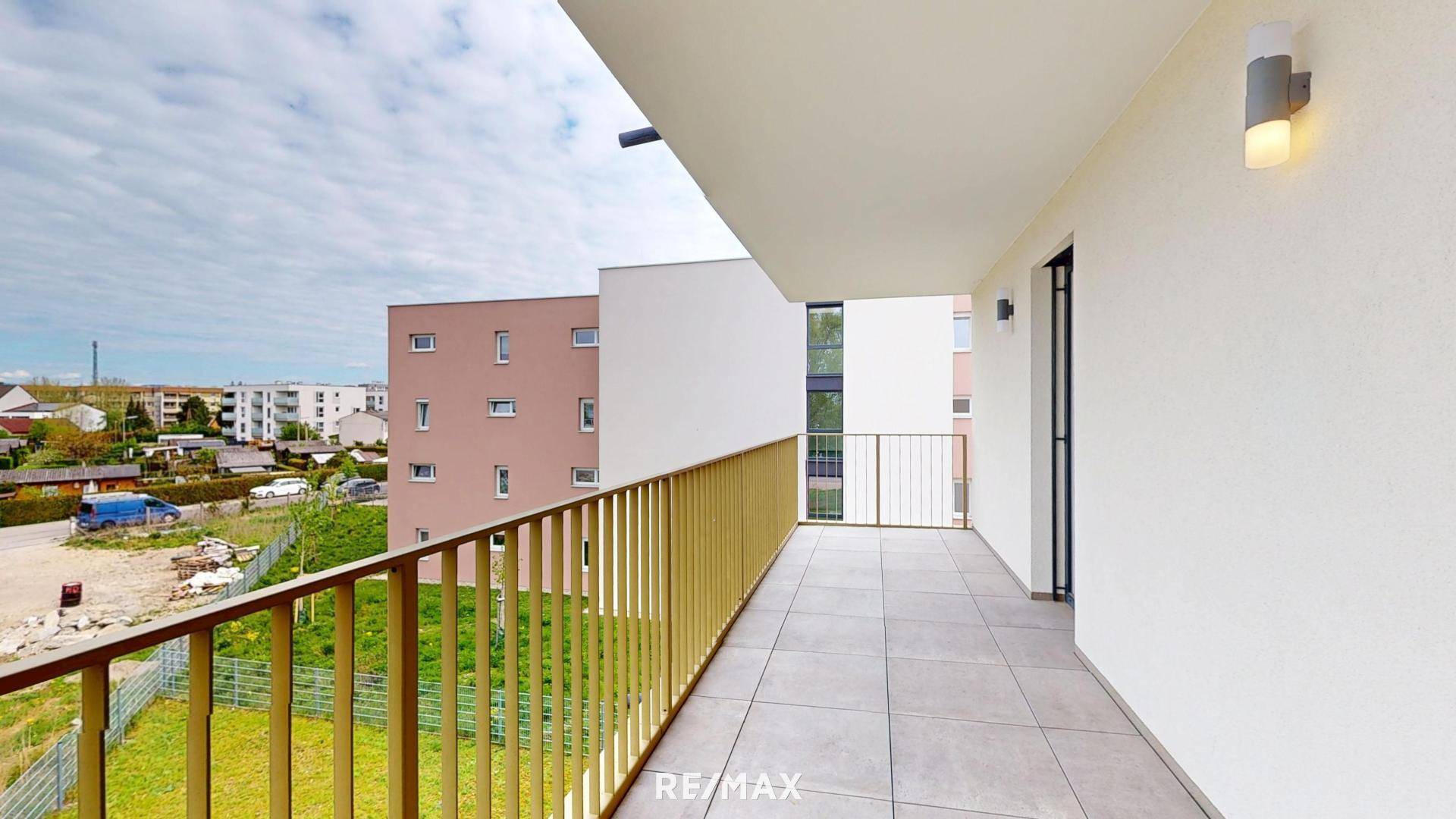 Geräumiger Balkon mit Fliesenboden und gelbem Geländer, bietet Blick auf die Umgebung.