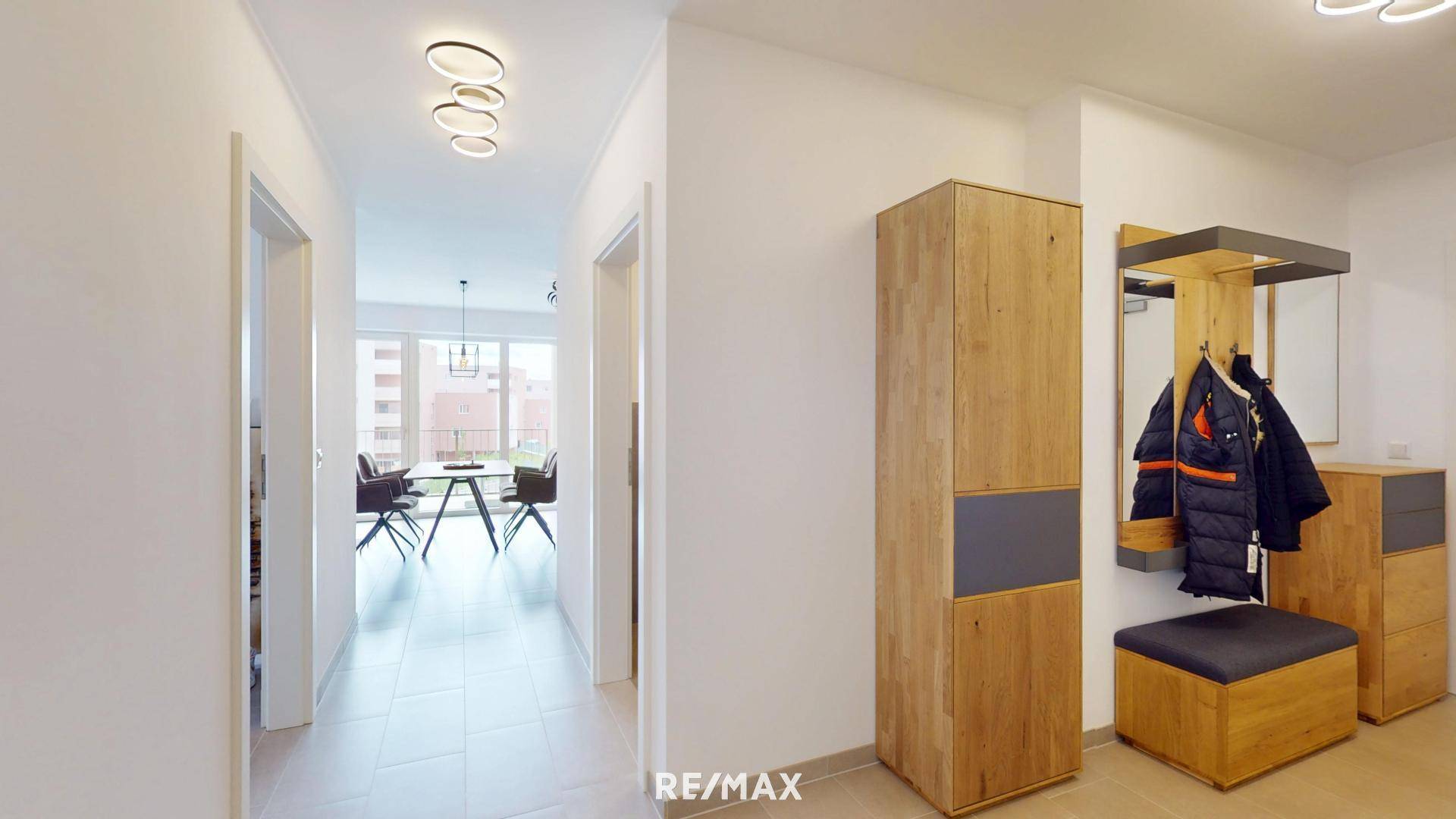 Heller Flur mit modernen Deckenleuchten und Garderobe, führt zu weiteren Räumen.