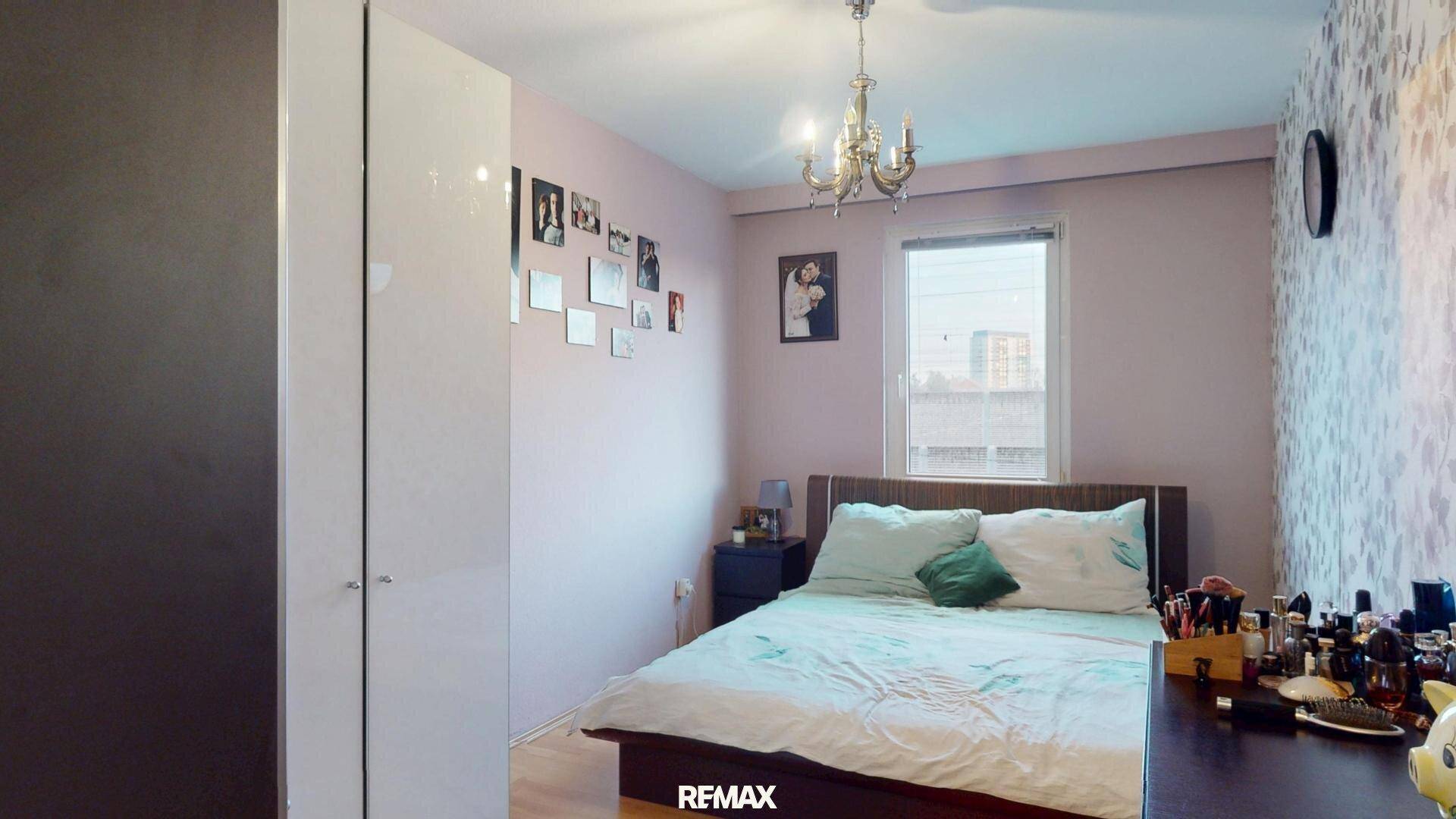 Gemütliches Schlafzimmer mit Doppelbett, Kleiderschrank und dekorativer Tapete an einer Wand.
