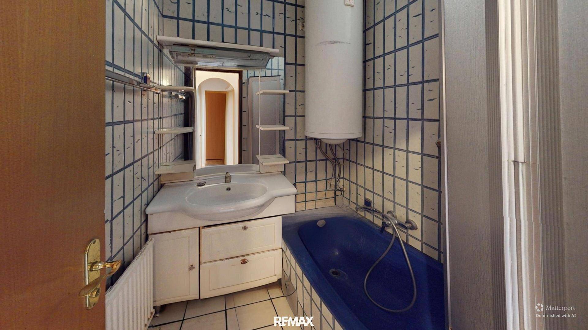 Badezimmer mit blauen und weißen Fliesen, Waschbecken und einer blauen Badewanne.