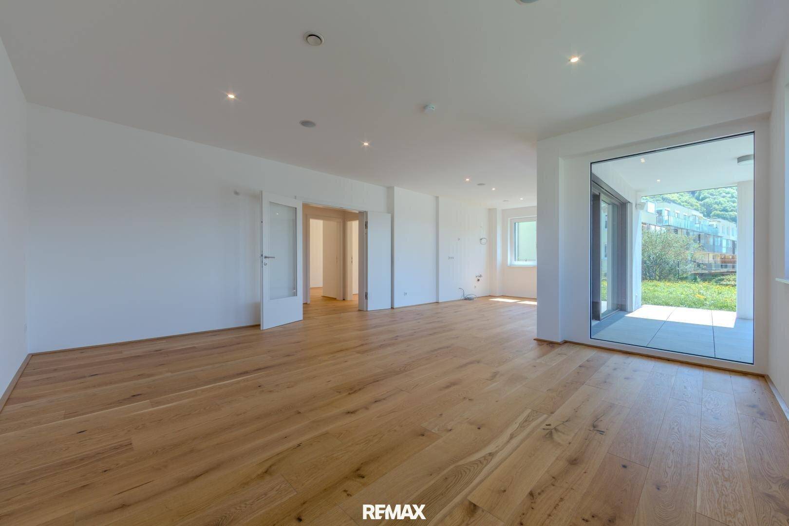 Großzügiger, offener Wohnbereich mit Holzboden und Zugang zu einer Außenterrasse.