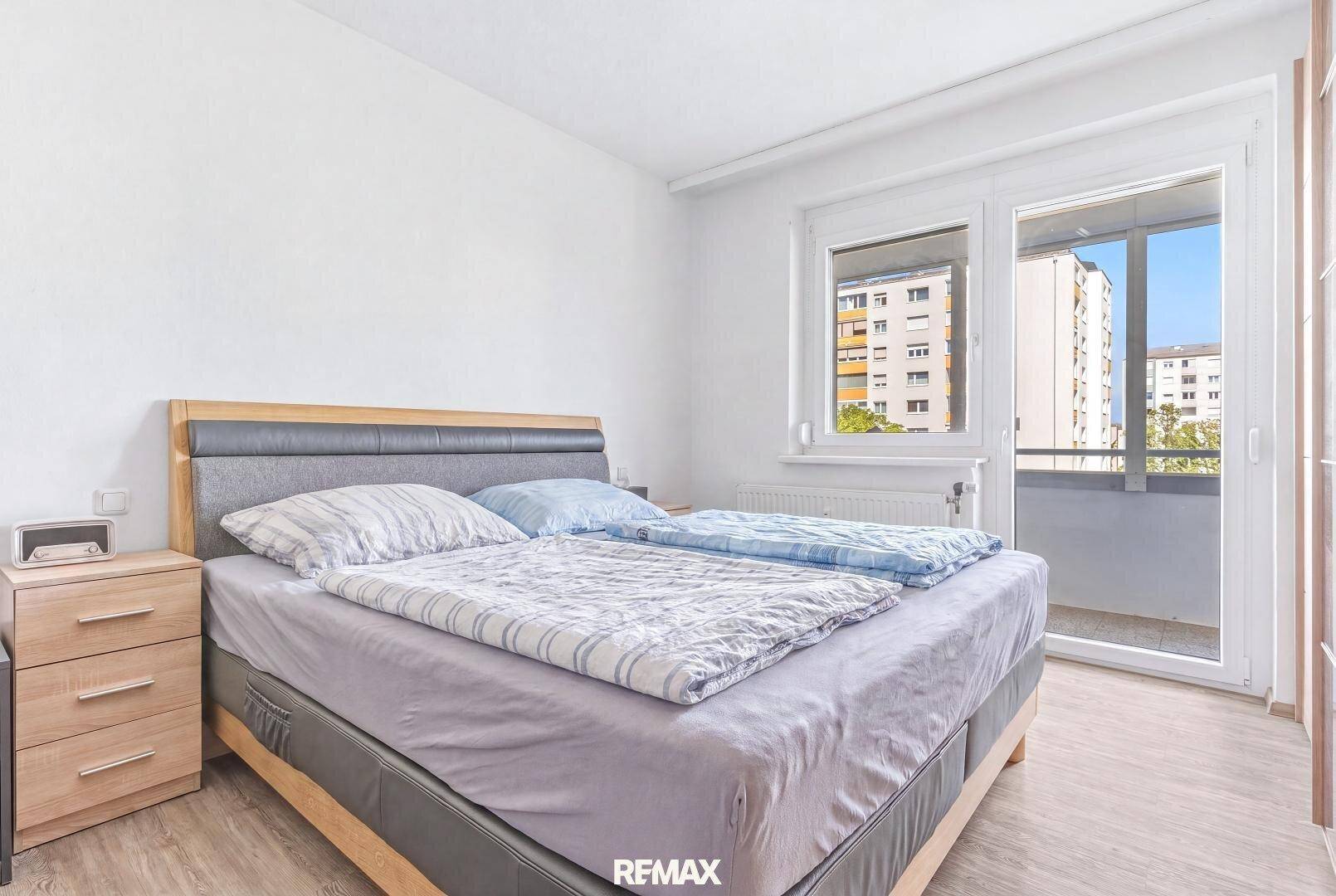 Schlafzimmer mit Doppelbett, Holzboden und direktem Zugang zu einem Balkon.