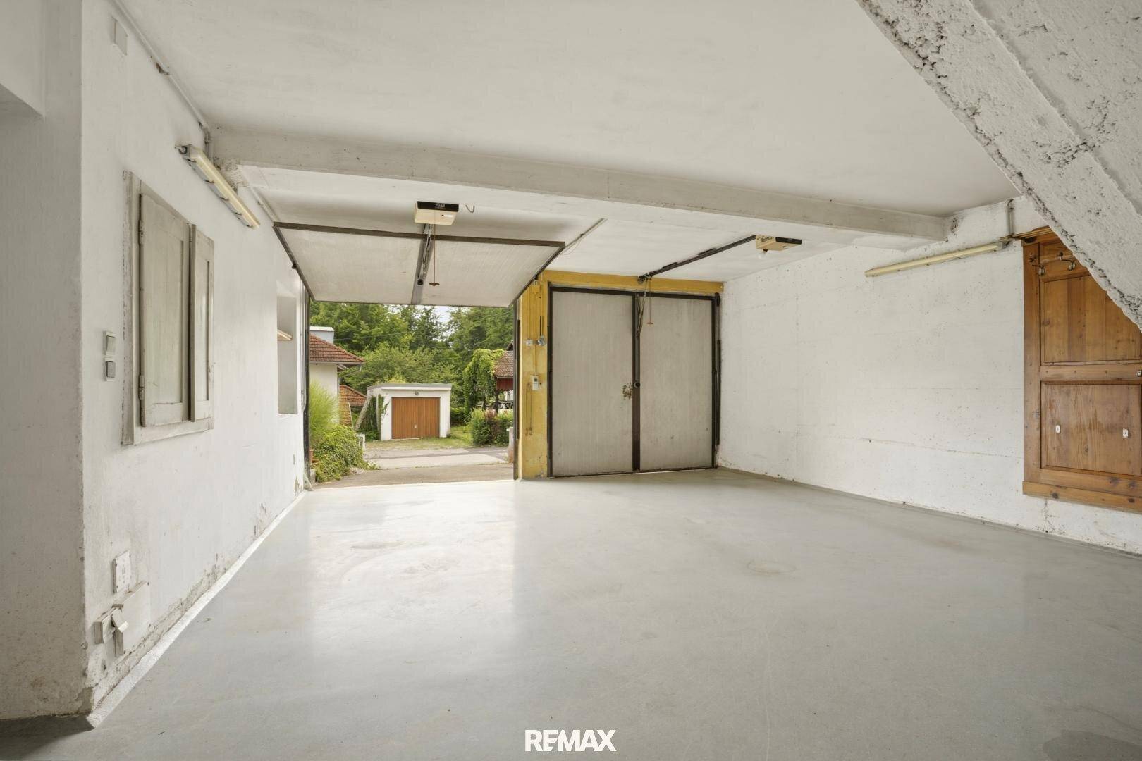Geräumige Garage mit Betonboden und zwei Garagentoren, bietet Platz für Fahrzeuge.