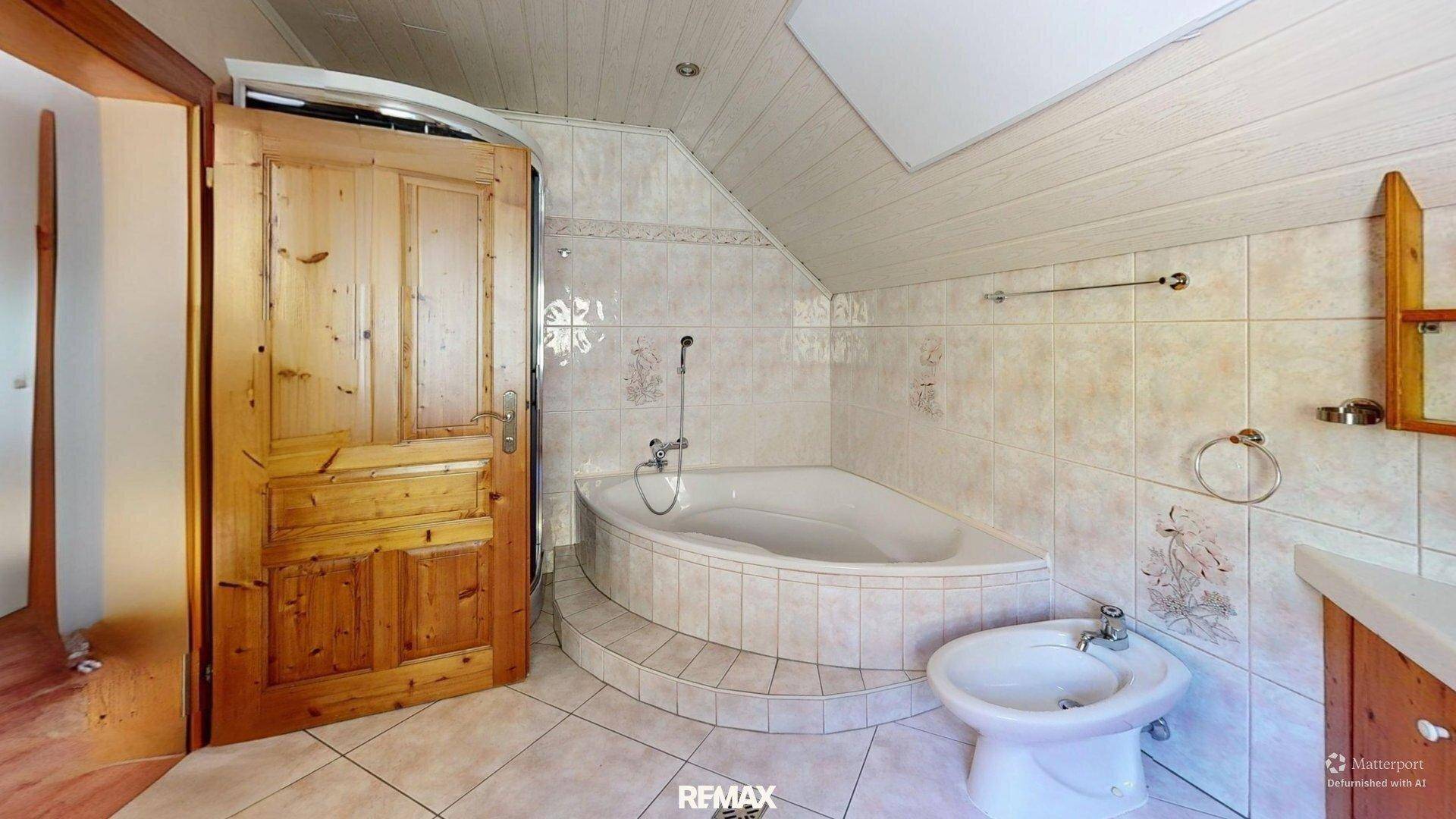 Helles Badezimmer im Dachgeschoss mit Eckbadewanne, Bidet und Holzdecke.