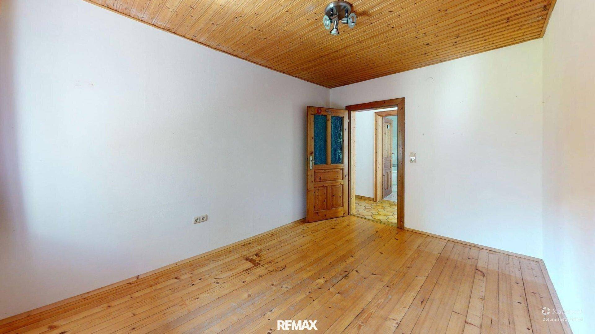 Geräumiges Schlafzimmer mit Holzboden, Holzdecke und Zugang zu weiteren Räumen.
