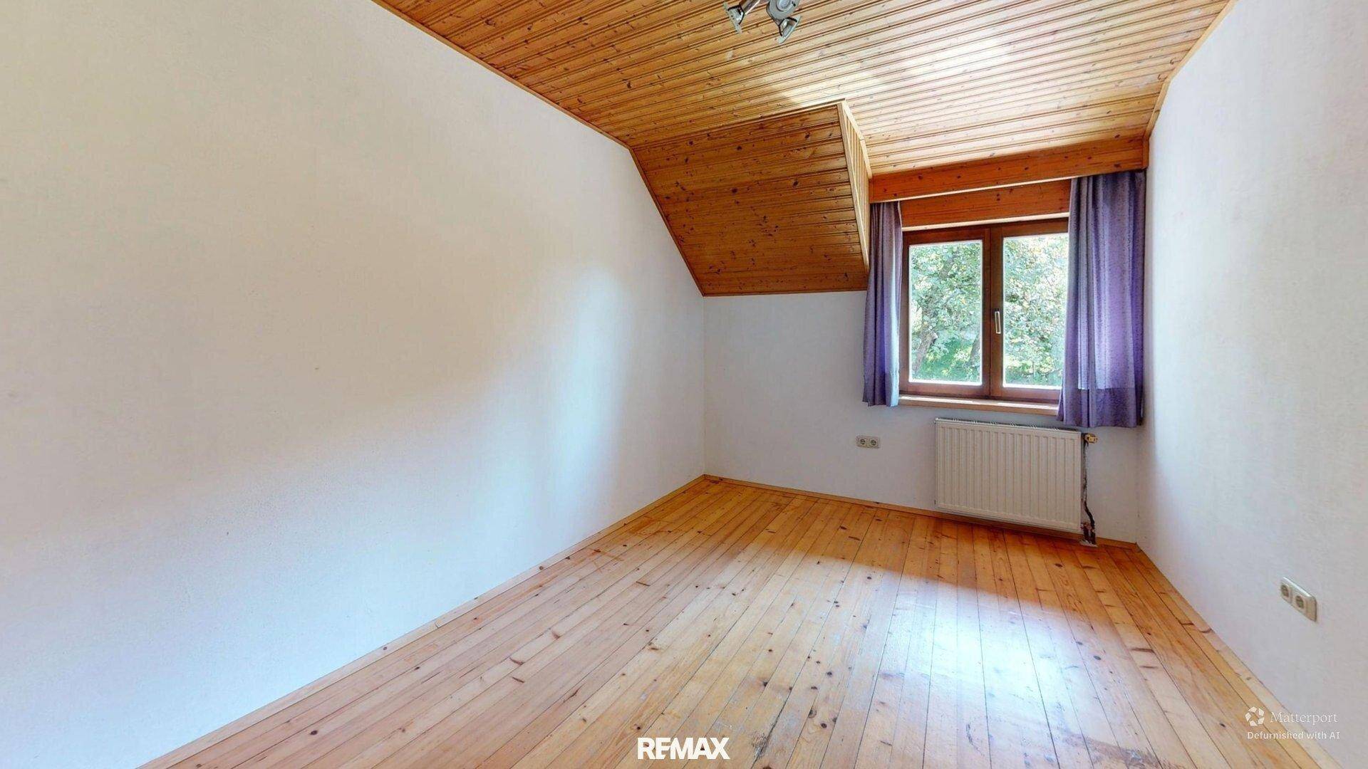 Helles Schlafzimmer mit Holzdecke, Holzboden und Fenster mit Blick ins Grüne.