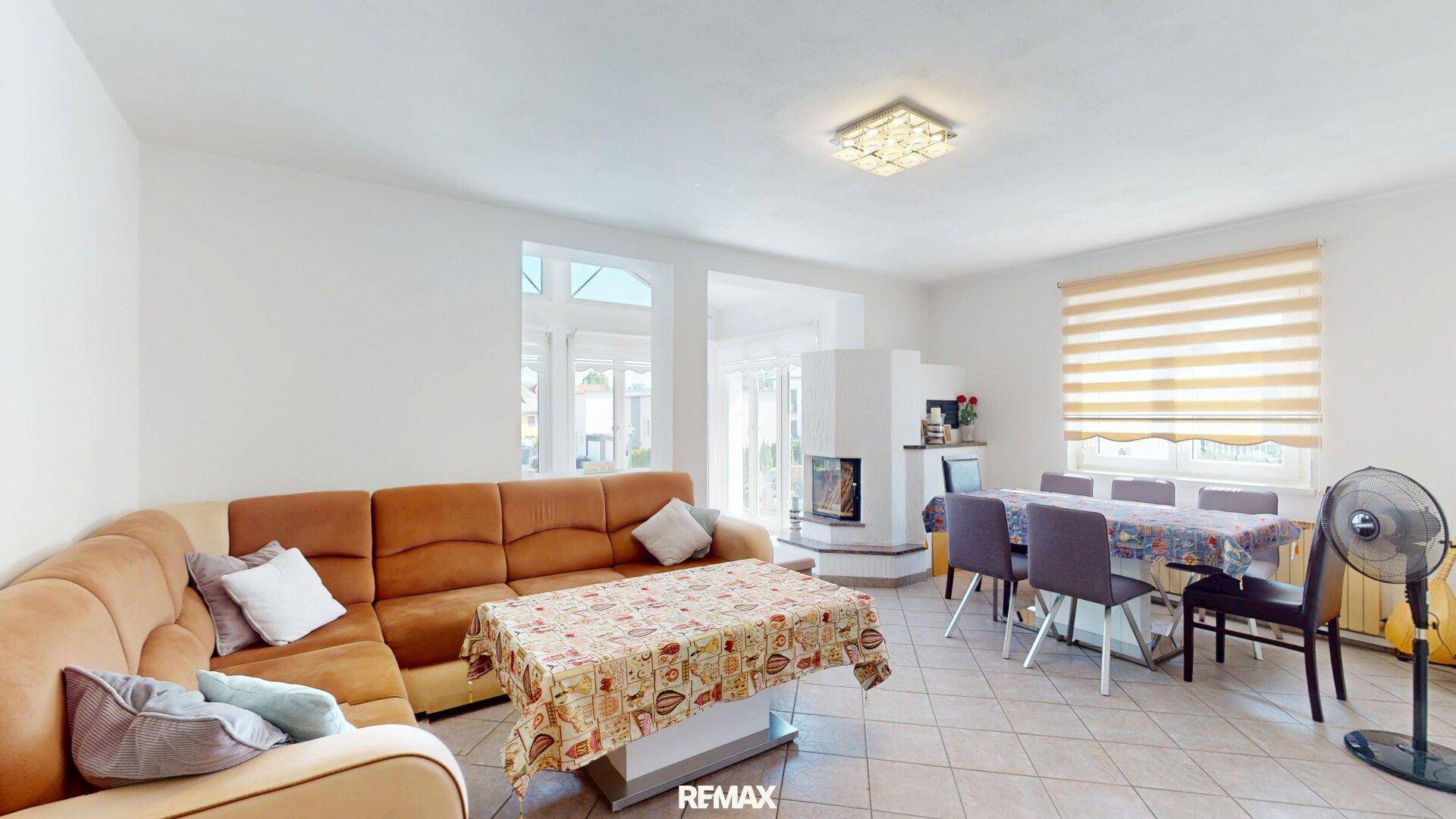 Geräumiger Wohn-Essbereich mit gemütlichem Sofa, Esstisch und einem dekorativen Kamin.