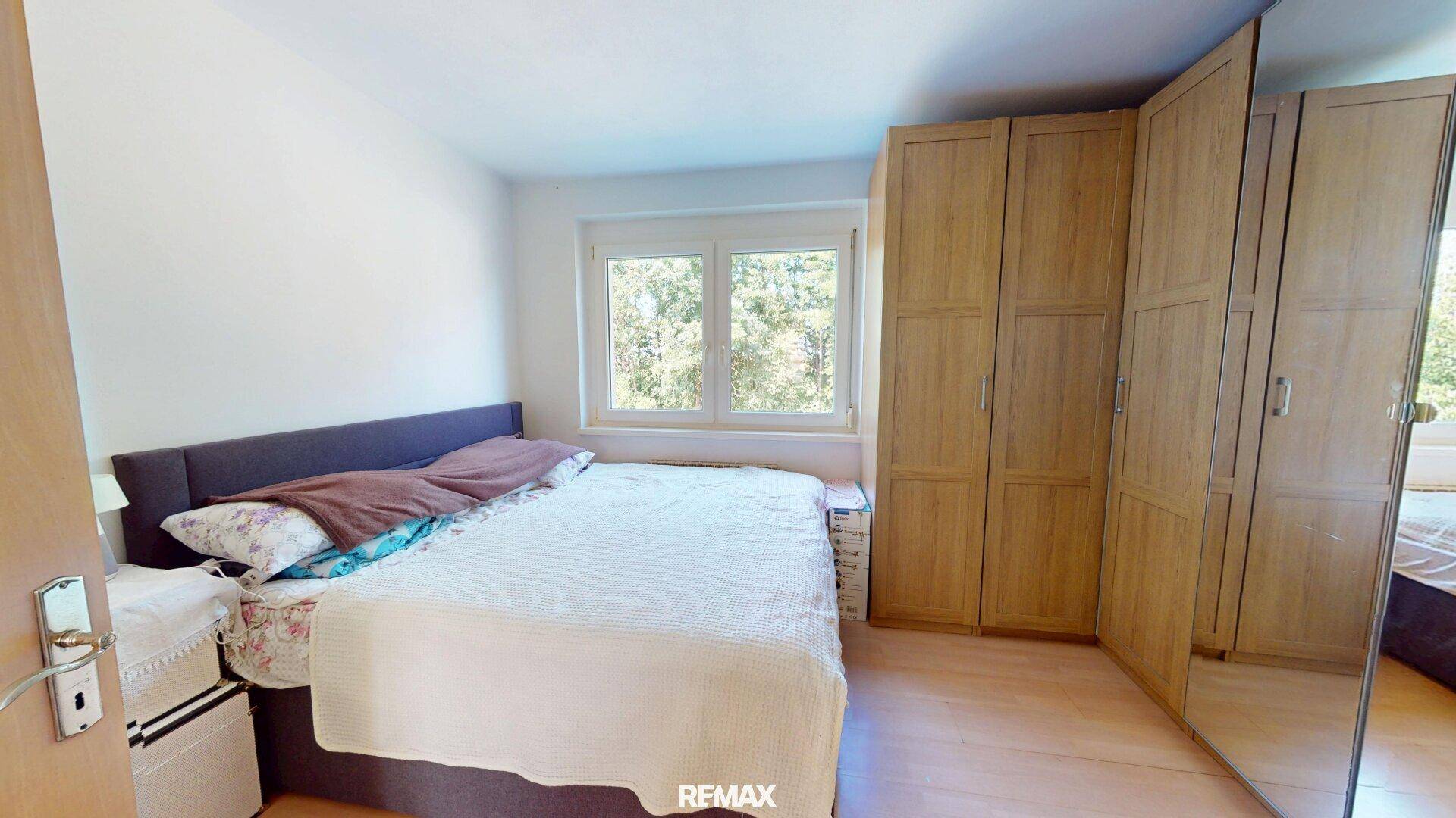 Helles Schlafzimmer mit Holzboden, großem Bett und praktischen Holzschränken.