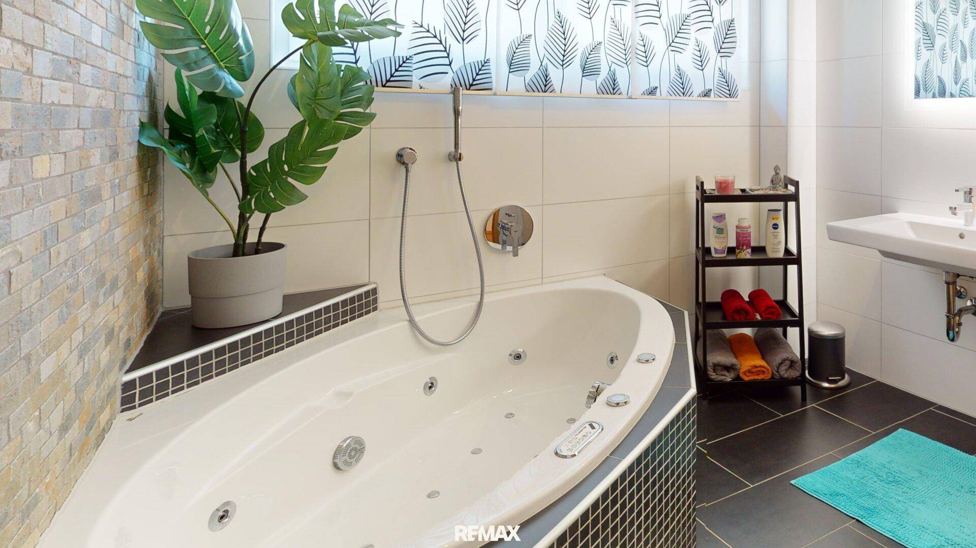 Modernes Badezimmer mit Eckbadewanne, Dusche und stilvollen Fliesen an den Wänden.