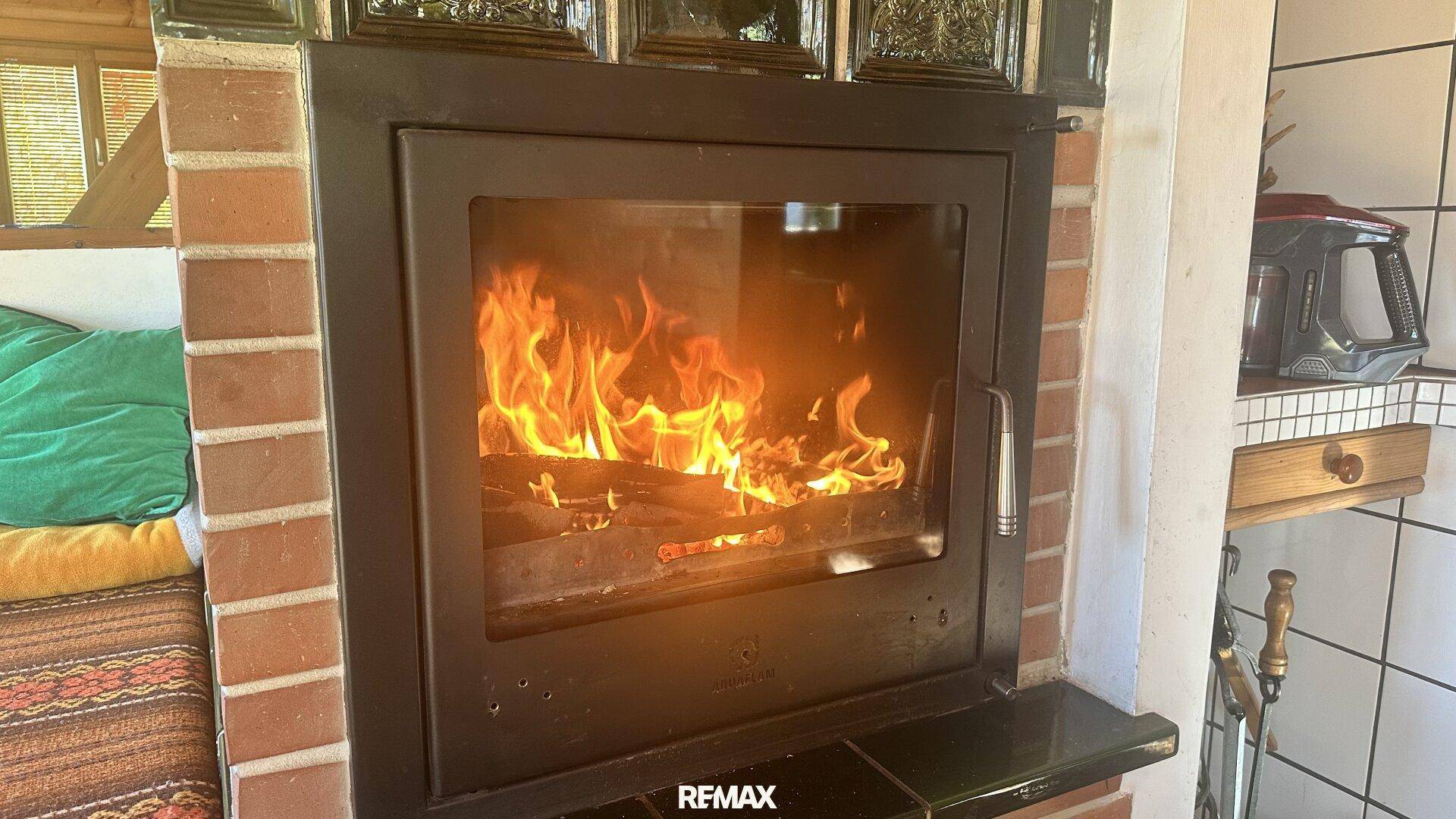 Gemütlicher Wohnbereich mit einem brennenden Kamin, umgeben von Ziegelsteinen und traditionellen Fliesen.