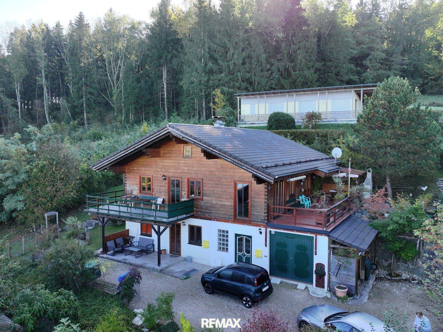 Idyllisches Holzhaus mit mehreren Balkonen und großem Gartenbereich in grüner Umgebung.